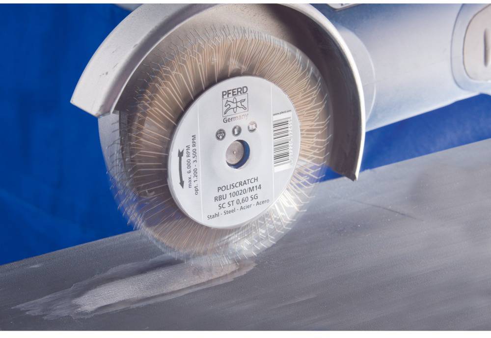 Eine rotierende Scheibenbürste bearbeitet die Oberfläche eines Metallstücks. Die Bürste entfernt Kratzer und poliert die Fläche.