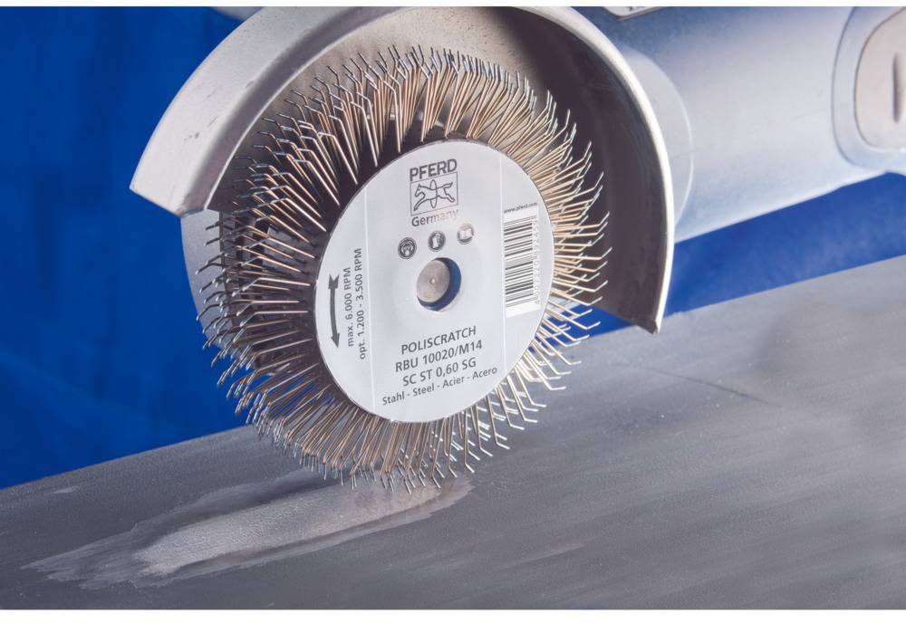 Eine rotierende Rundbürste poliert eine Metalloberfläche. Die Bürste zeigt den Schriftzug 'PFERD Germany', auf einem blauen Hintergrund.