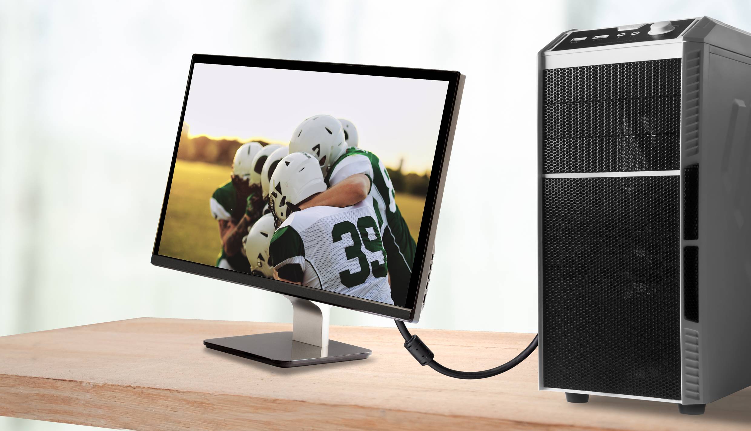 Ein Computerbildschirm zeigt ein Team von American Football-Spielern, die sich umarmen. Ein angeschlossener Computer steht rechts.