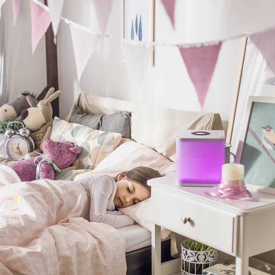Ein Kind schläft friedlich in einem Bett mit weicher Bettwäsche und Kuscheltieren, umgeben von sanftem Licht und dekorativen Wimpeln.