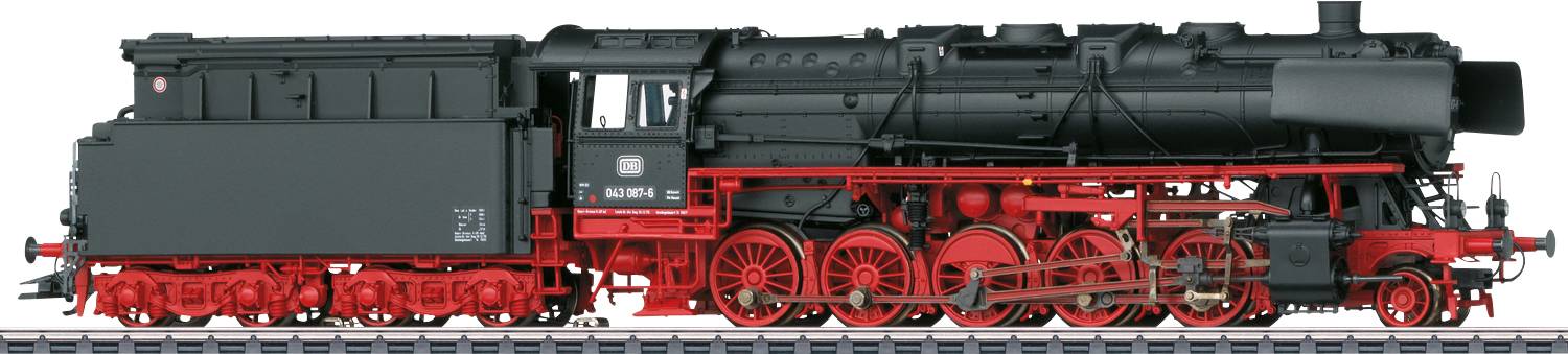 Eine schwarze Dampflokomotive mit roten Details steht auf Gleisen. Sie hat einen langen Schornstein und mehrere Räder mit sichtbaren Mechaniken.