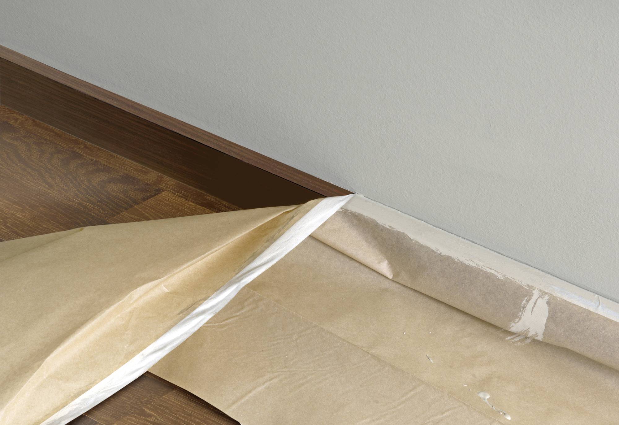 Ein Teil von einem Bodenbelag wird verlegt. Ein braunes Unterlegpapier liegt auf dem Boden, teilweise zurückgeschlagen.