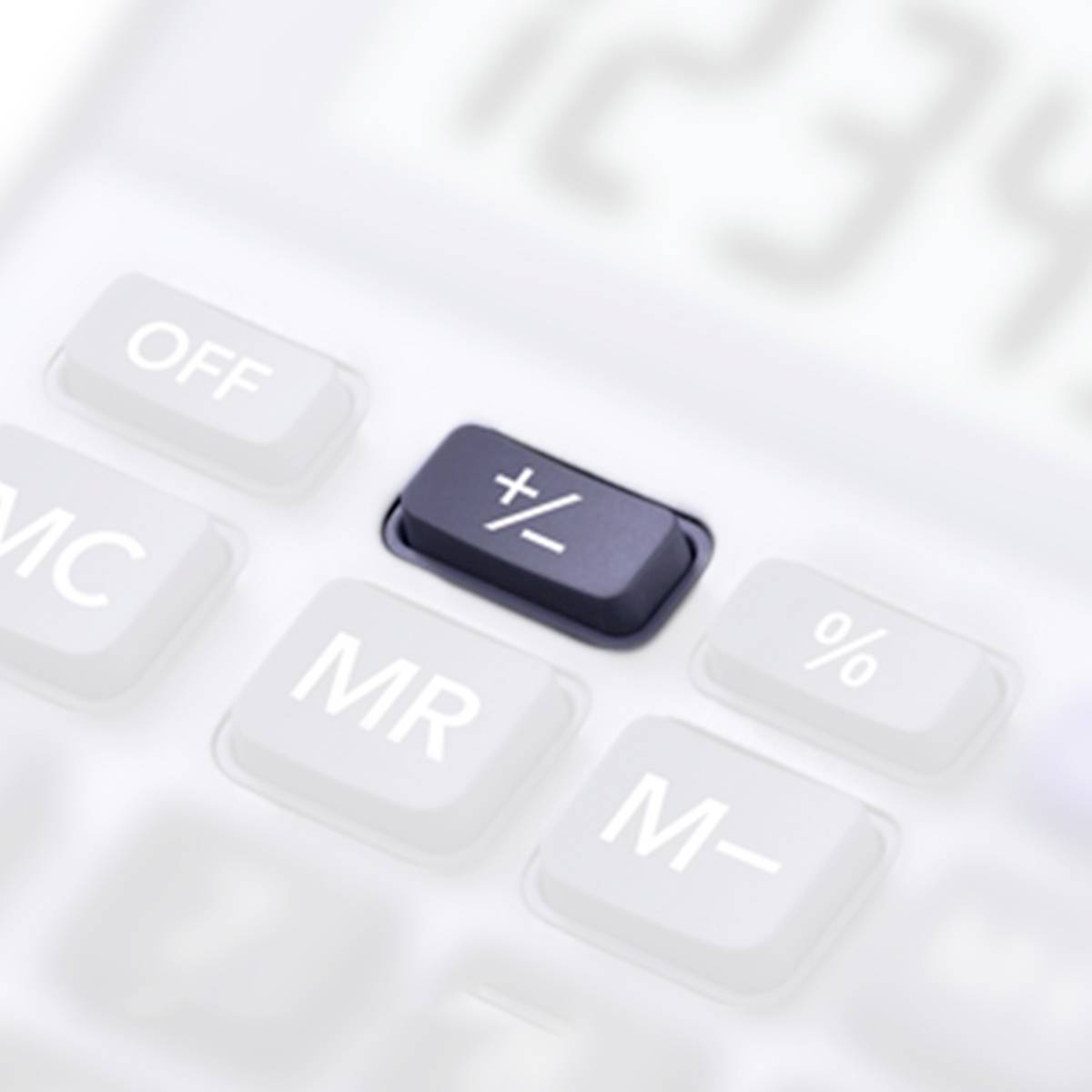 Nahaufnahme einer weißen Taschenrechner-Tastatur mit hervorgehobener Plus-Minus-Taste.