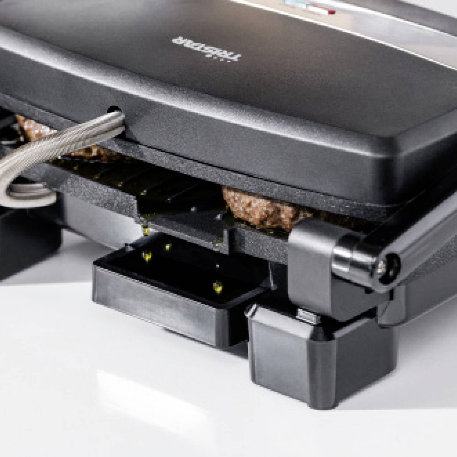 Ein Kontaktgrill, der zwei Burger-Patties grillt. Der Grill ist teilweise geöffnet und zeigt die Fleischstücke zwischen den Platten.