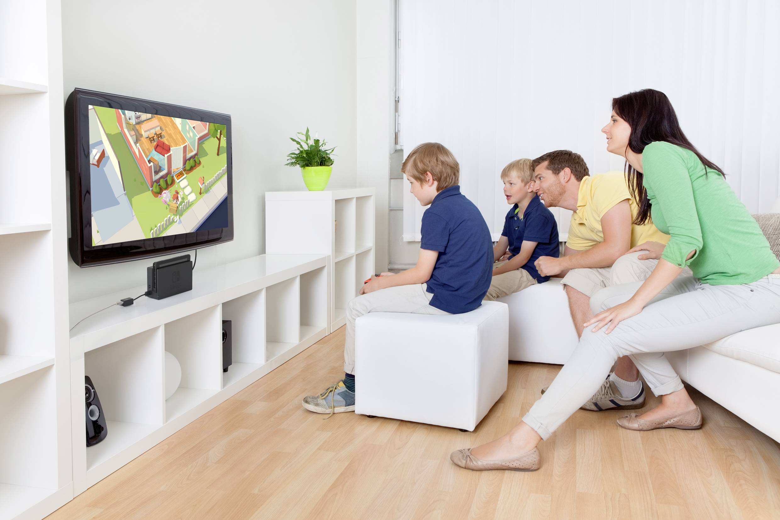 Eine Familie sitzt im Wohnzimmer und sieht Cartoons im Fernsehen. Drei Kinder und ein Erwachsener schauen konzentriert auf den Bildschirm.