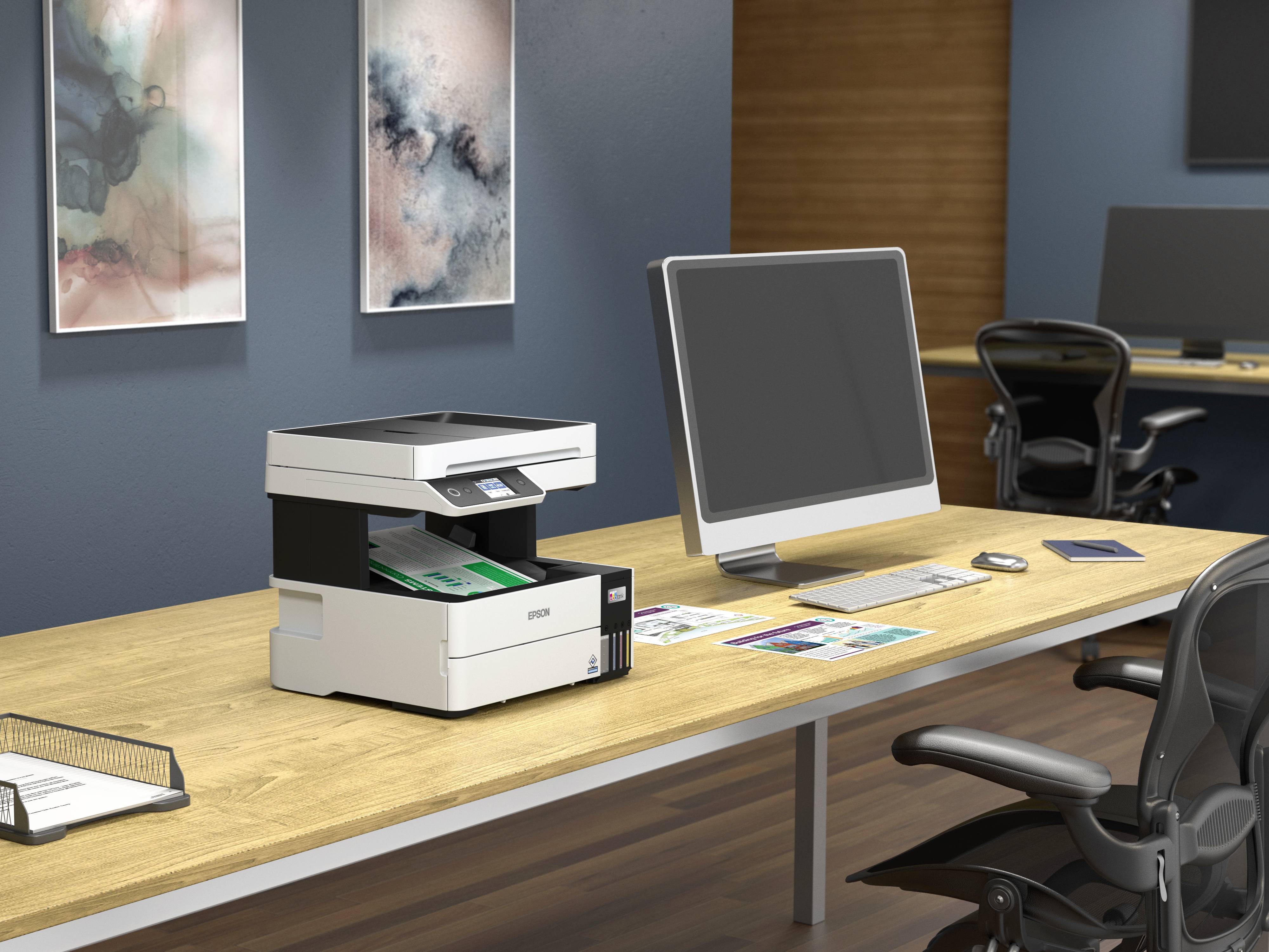 Ein Drucker steht auf einem Holzschreibtisch, umgeben von einem Computer, Stühlen und Papierdokumenten in einem modernen Büro.