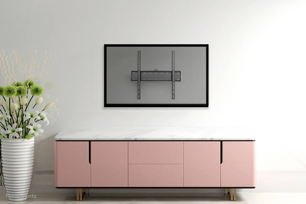 Eine leere rosa Anrichte steht vor einer weißen Wand. Darüber ist eine leere TV-Wandhalterung montiert. Links steht eine Vase mit weißen Blumen.