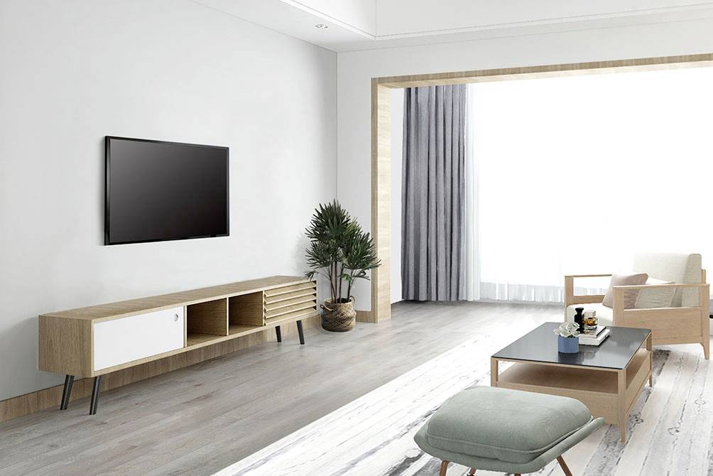 Helles, modernes Wohnzimmer mit Holzfußboden, TV an der Wand, Holzmöbeln, Sofa und großem Fenster mit Vorhängen.