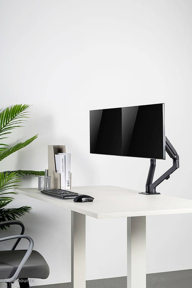 Moderner Schreibtisch mit ergonomischem Monitorarm, Tastatur, Maus und stilvollem Dekor; minimalistische Büroeinrichtung.