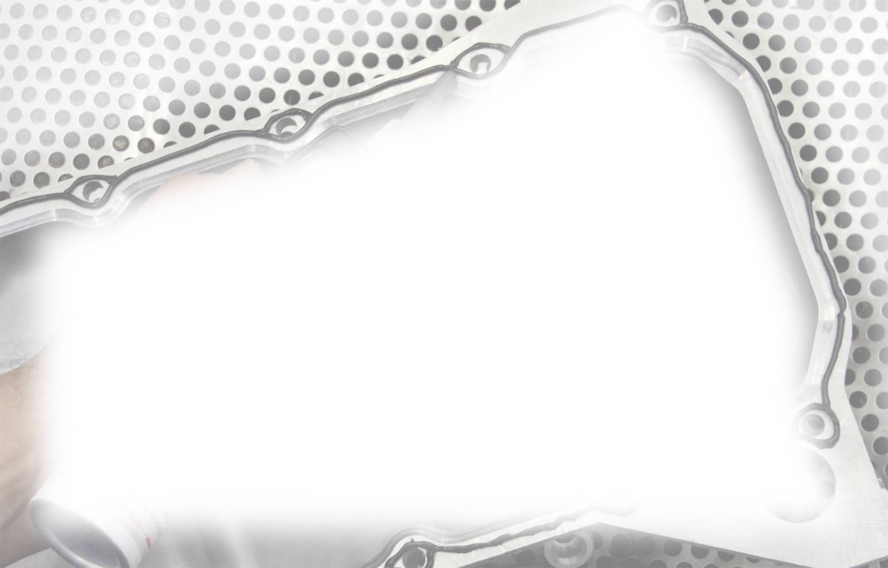 Metallische Struktur mit sechseckigem Muster und einem helleren, unregelmäßigem Bereich in der Mitte, der wie ein Lichtreflex aussieht.