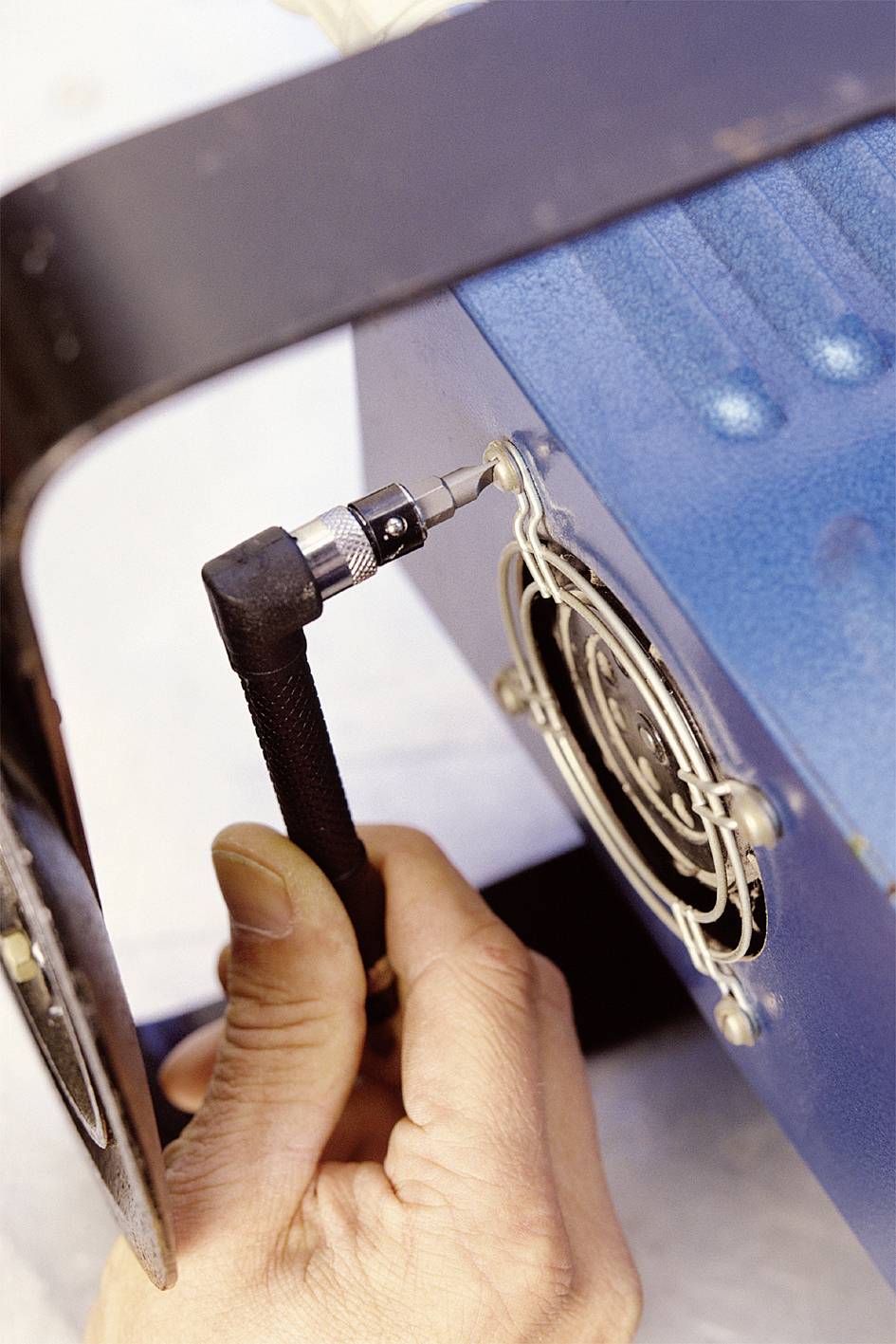 Hand hält Schraubendreher, schraubt Lüfter an blauem Gehäuse fest.