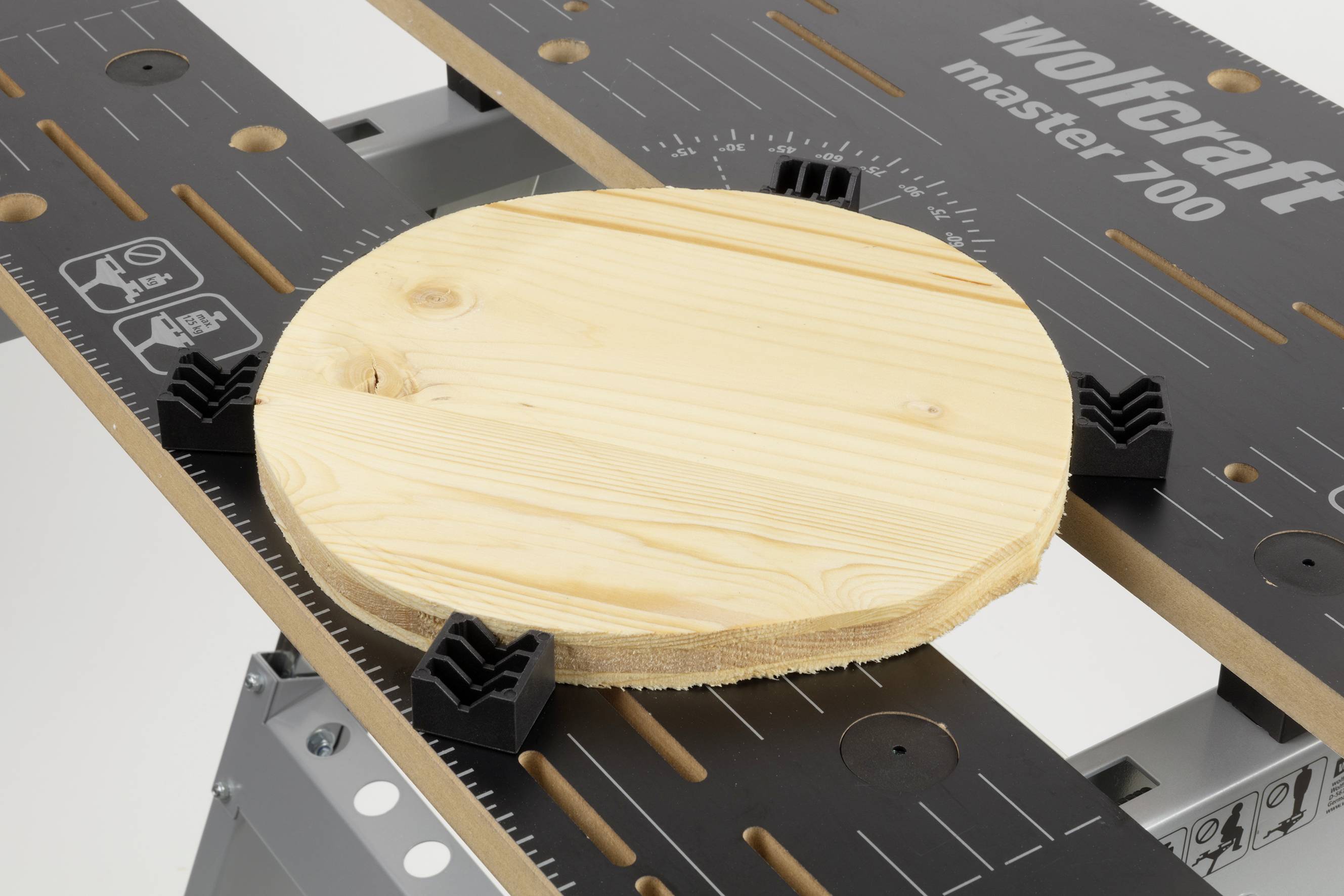 Holzrundes Stück auf einem Wolfcraft Master 700 Tisch montiert, umgeben von Klemmen zum sicheren Halt und Bearbeiten.