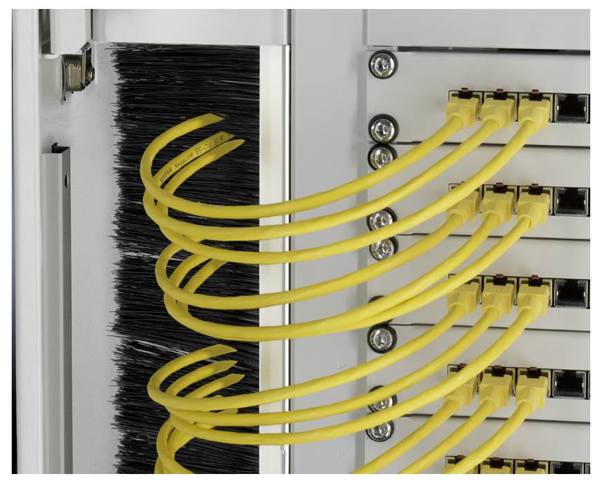 Gelbe Glasfaserkabel sind in Schlitzen eines Serverracks organisiert, verlaufen spiralförmig und verbinden Netzwerkkomponenten.