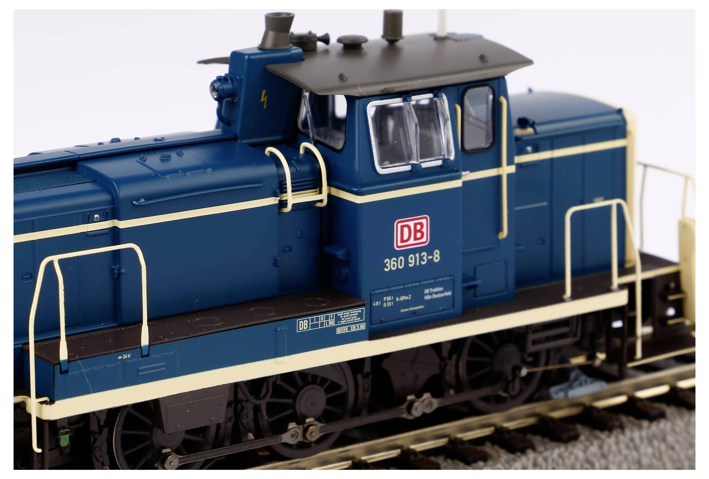 Ein blaues Modell einer DB-Lokomotive auf Gleisen, mit weißen Geländern und grauem Dach. Aufschrift: '360 913-8'.