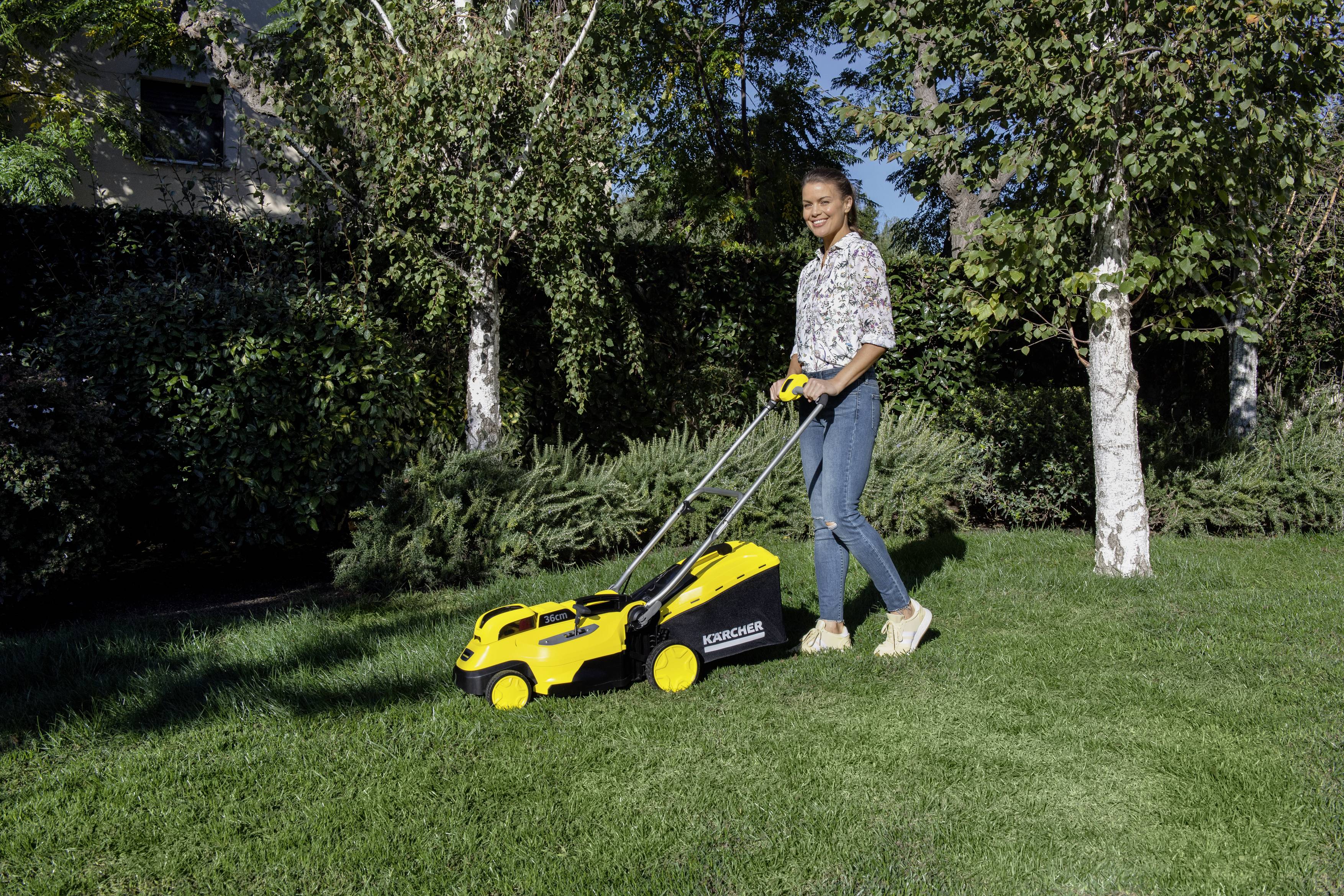 Eine Person mäht Rasen im Garten mit einem gelben Rasenmäher an einem sonnigen Tag. Im Hintergrund sind Büsche und Bäume.