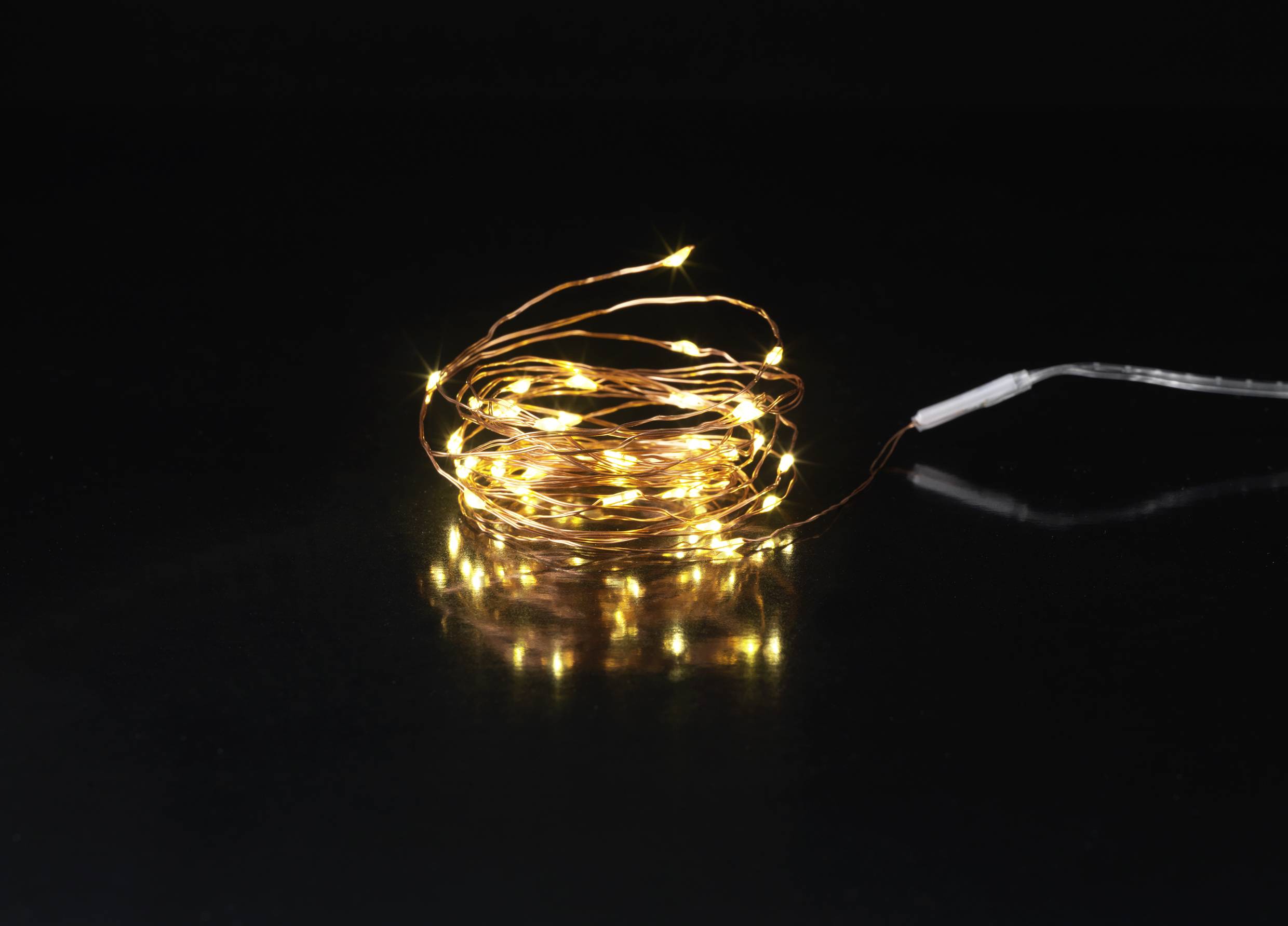 Lichterkette mit warmweißen Leuchten auf dunklem Hintergrund. Sie sind spiralförmig angeordnet und erzeugen ein gemütliches Licht.