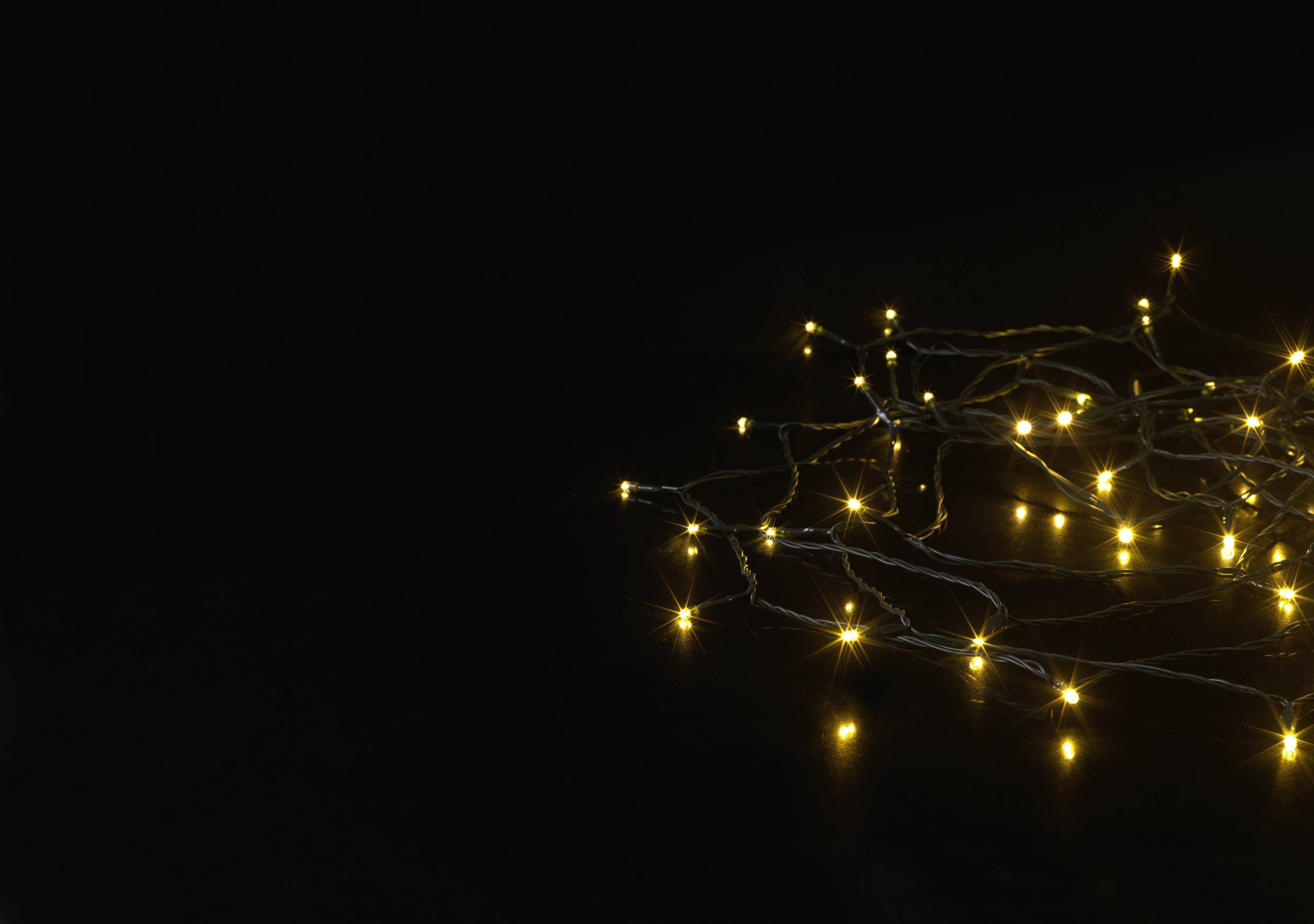 Eine Lichterkette mit warmen gelben LEDs liegt auf einem dunklen Hintergrund, verbreitet ein sanftes, einladendes Licht.