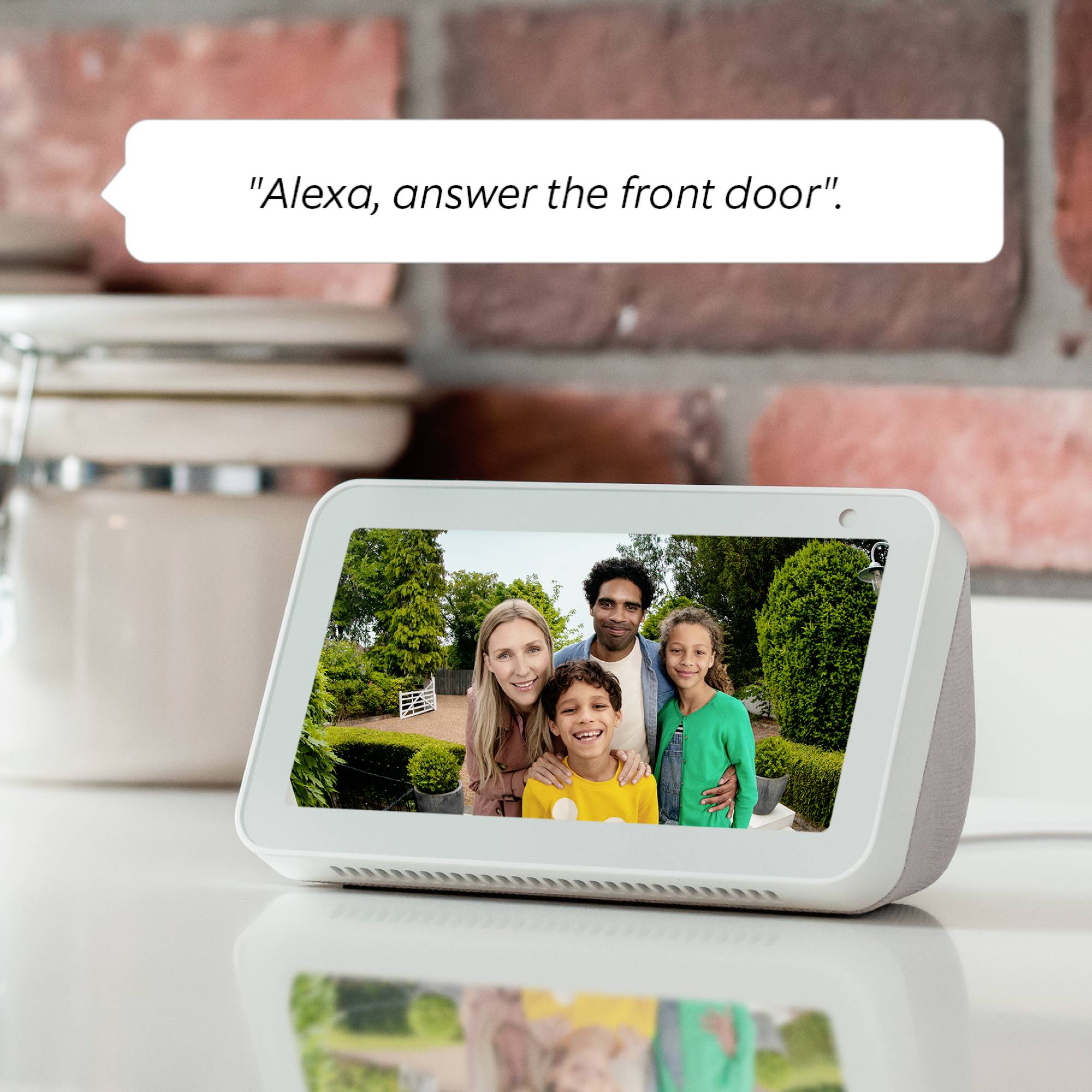 Ein intelligentes Display zeigt ein Familienfoto. Text im Bild: 'Alexa, answer the front door'.