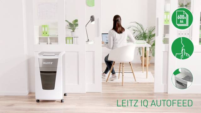 Eine Frau arbeitet am Schreibtisch. Im Vordergrund steht ein Leitz Aktenvernichter. Rechts Symbole: 600 Blatt Kapazität, Auto-Feed-Funktion.