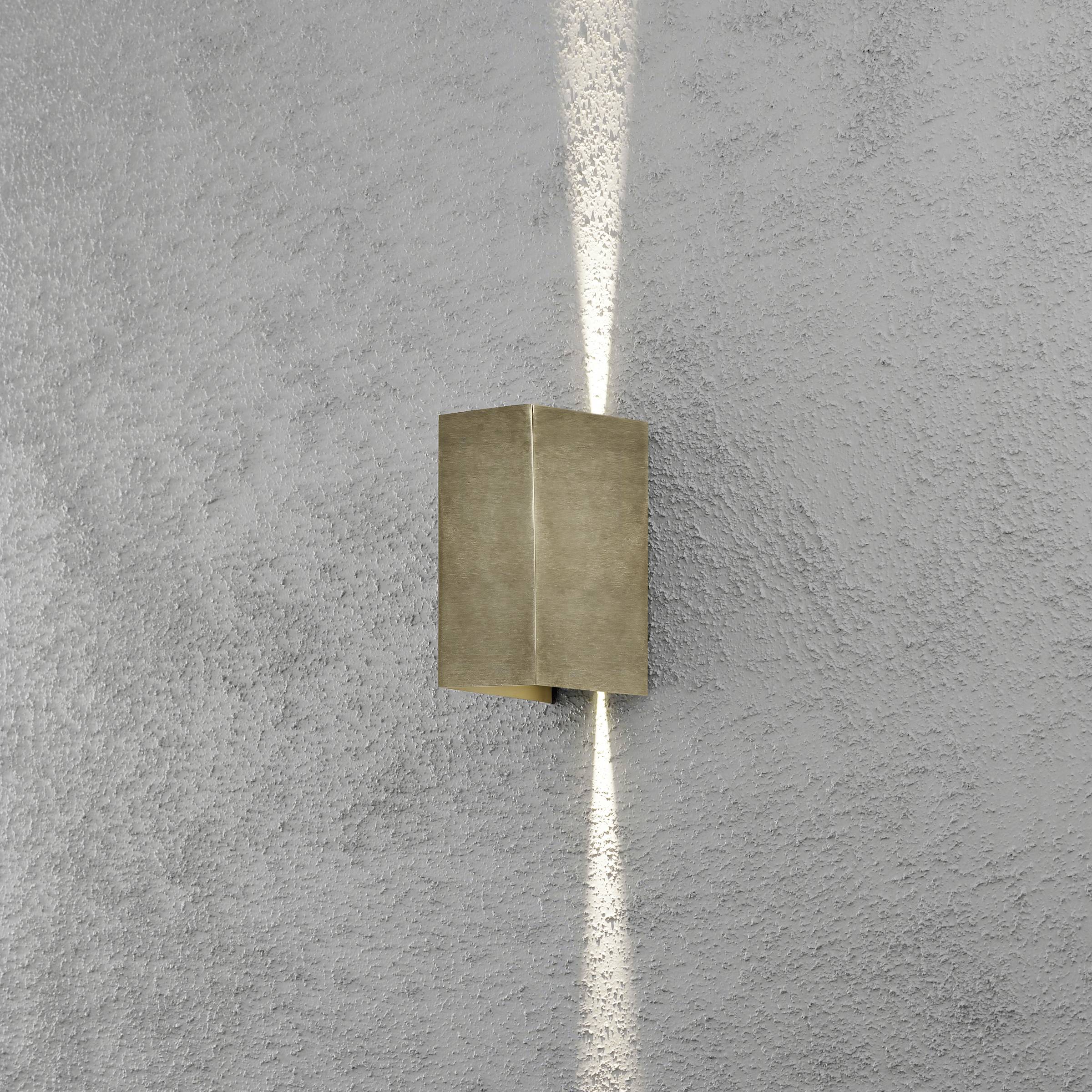 Wandleuchte vor grauer Wand strahlt warmes Licht nach oben und unten. Rechteckiges Design in Metalloptik. Beleuchtete Akzentuierung.