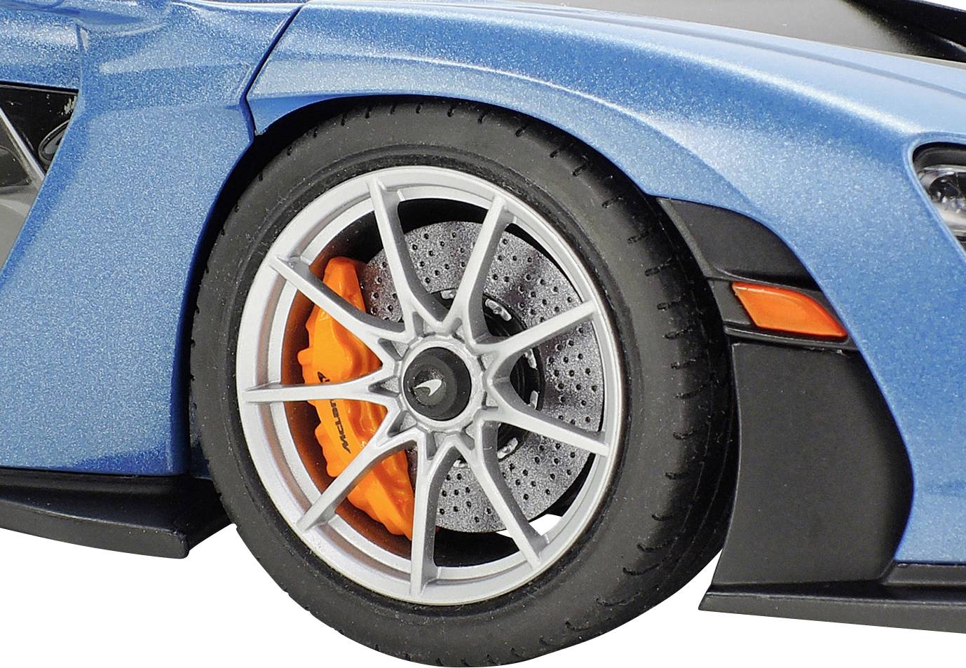 Nahaufnahme eines blauen Autos zeigt den linken Vorderreifen mit einer orangen Bremse hinter einer silbernen Felge.