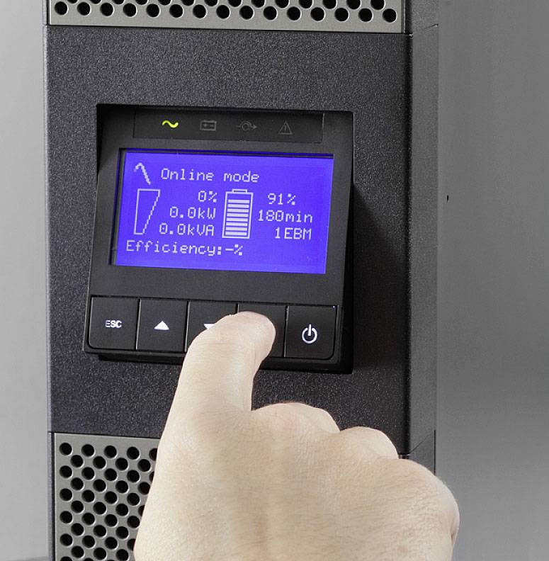 Ein Finger drückt eine Taste auf einem Display, das den Online-Modus eines Geräts zeigt: 0kW, 0kVA, 91% Batterie, 180 Min.