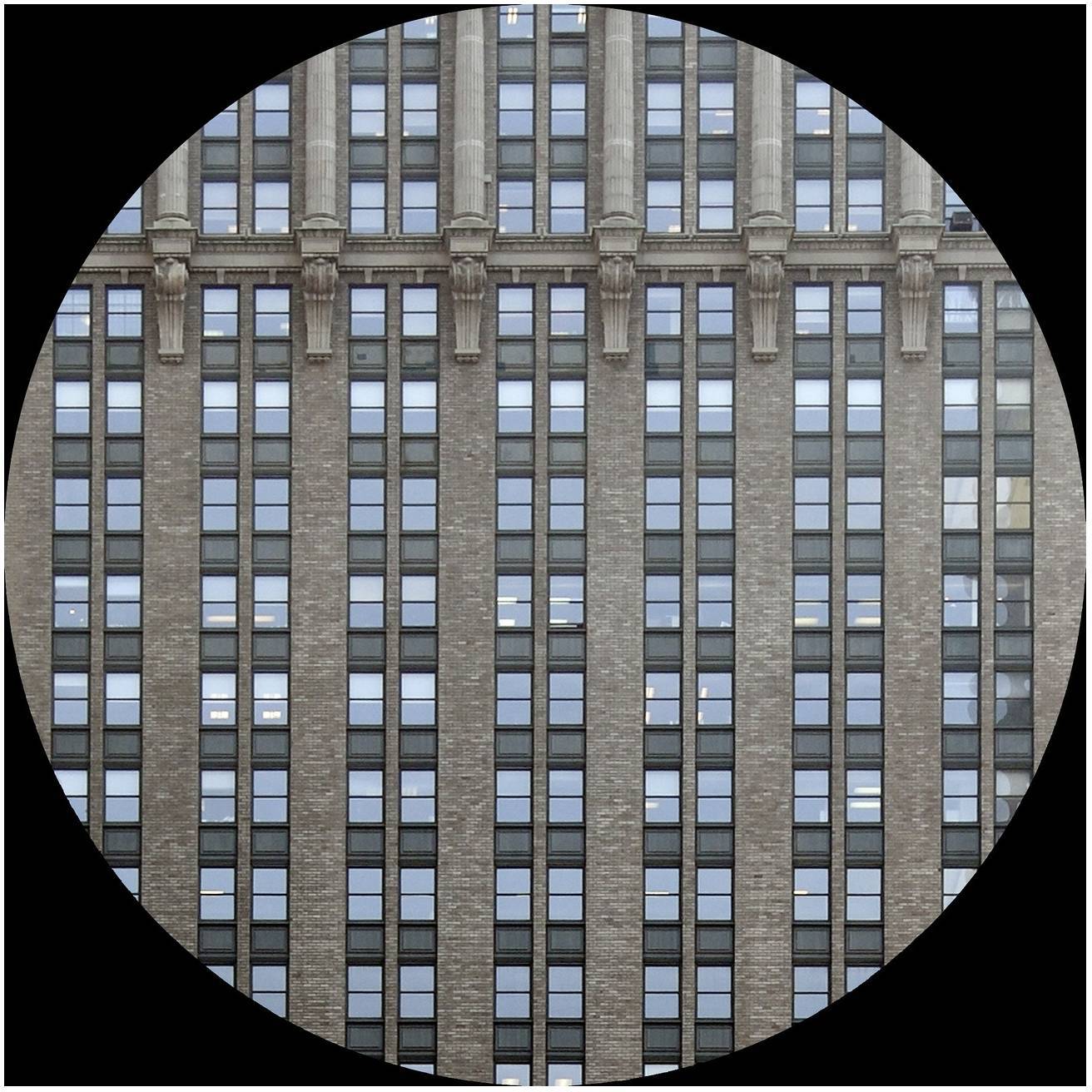Ein historisches Hochhaus mit Backsteinfassade und regelmäßigen Fensterreihen in einem zylindrischen Rahmen.