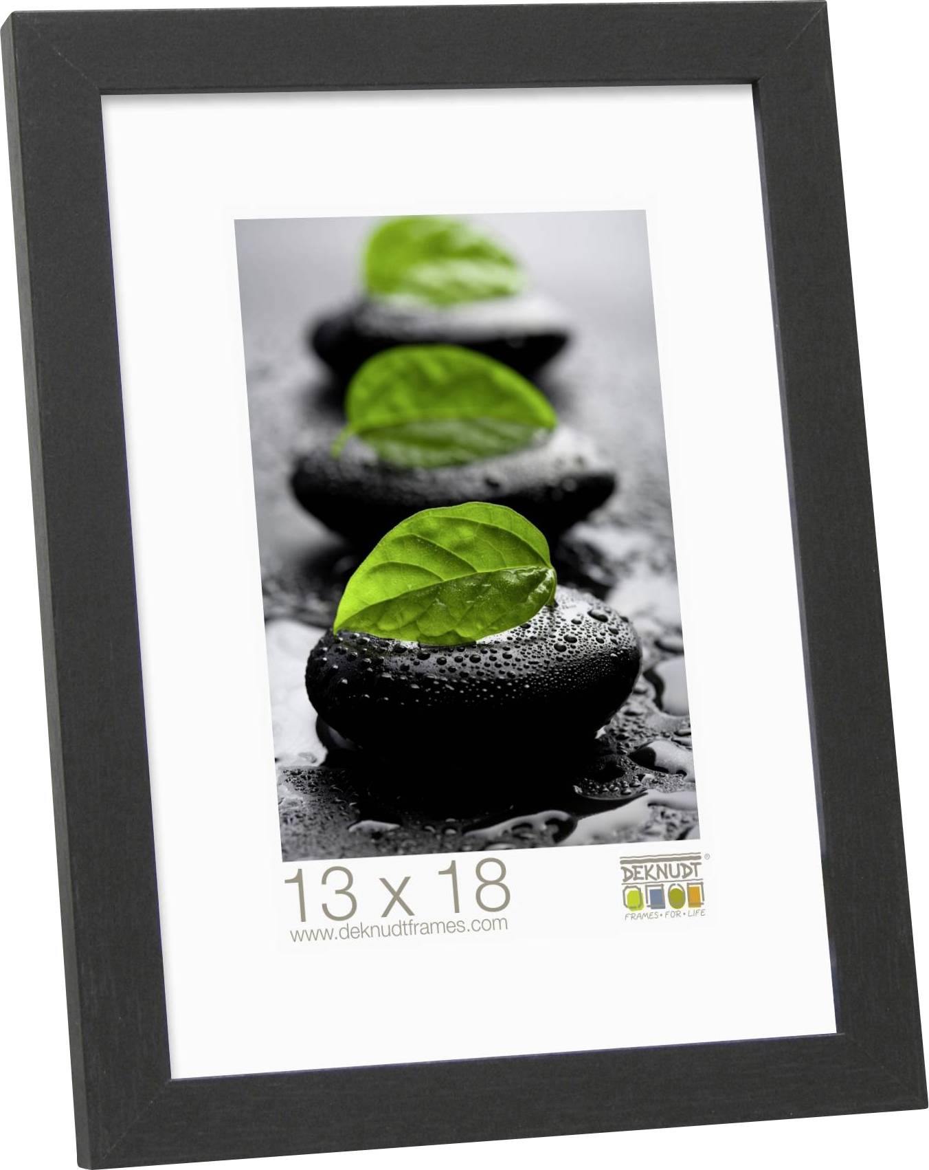 Ein Bilderrahmen mit dem Foto von drei nassen Steinen, auf denen jeweils ein grünes Blatt liegt. Formatangabe: 13 x 18 cm.