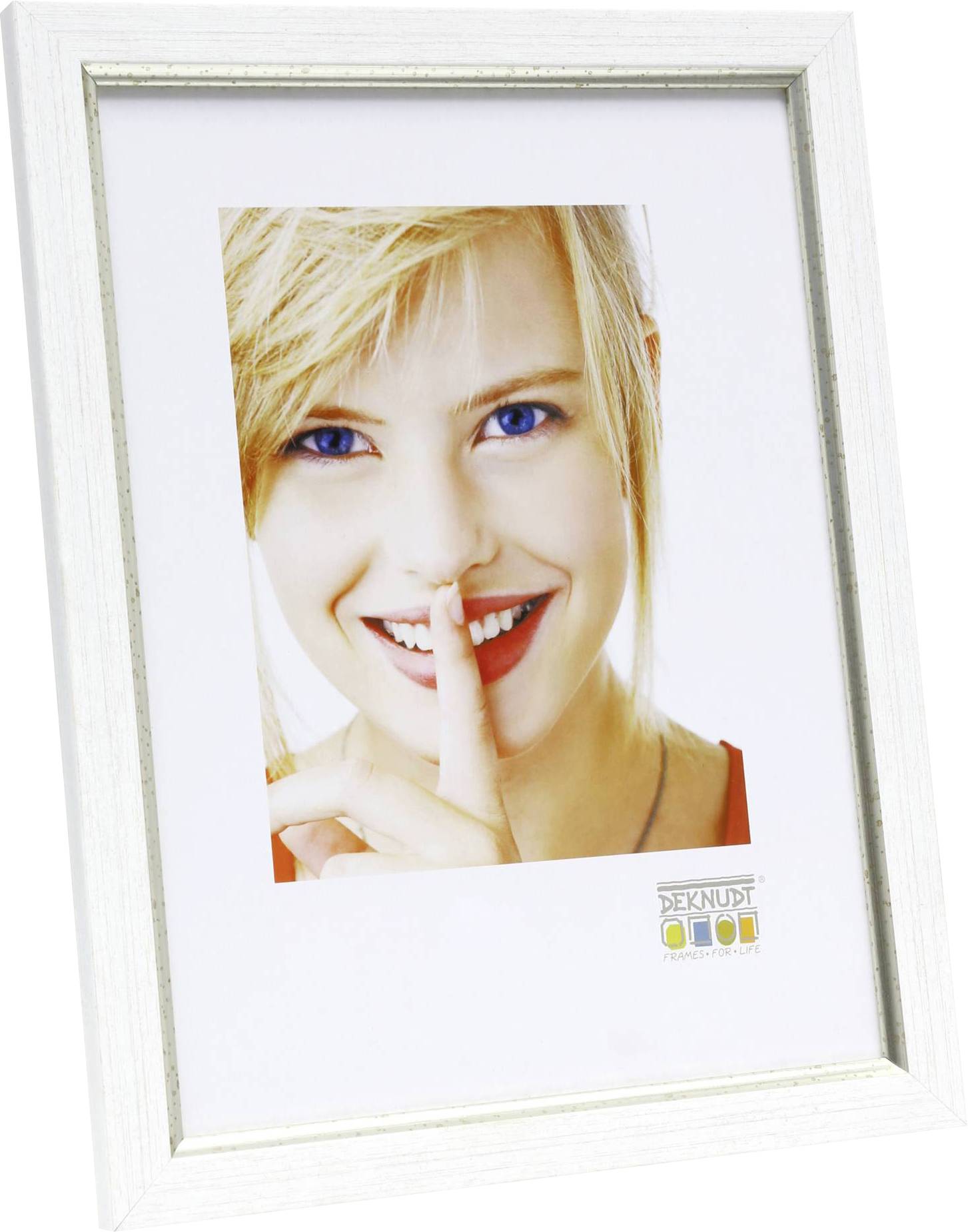 Eine Frau mit blonden Haaren lächelt und legt ihren Finger auf die Lippen, als ob sie 'Pssst' sagt.