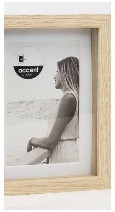 Eine Person steht draußen an einem Geländer und schaut in die Ferne. Das Bild ist in einem Holzrahmen und hat das Logo 'accent' von 'nielsen'.