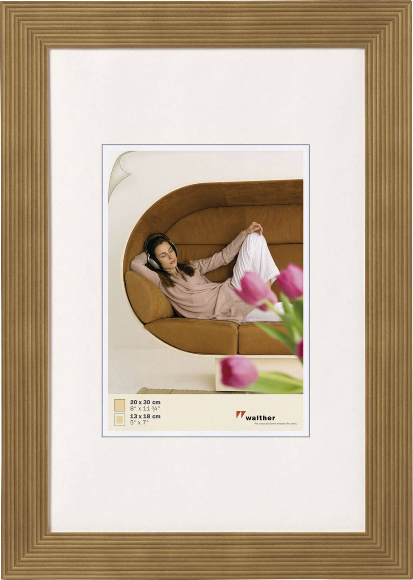 Frau entspannt auf braunem Sofa, eine Vase mit rosa Tulpen im Vordergrund.