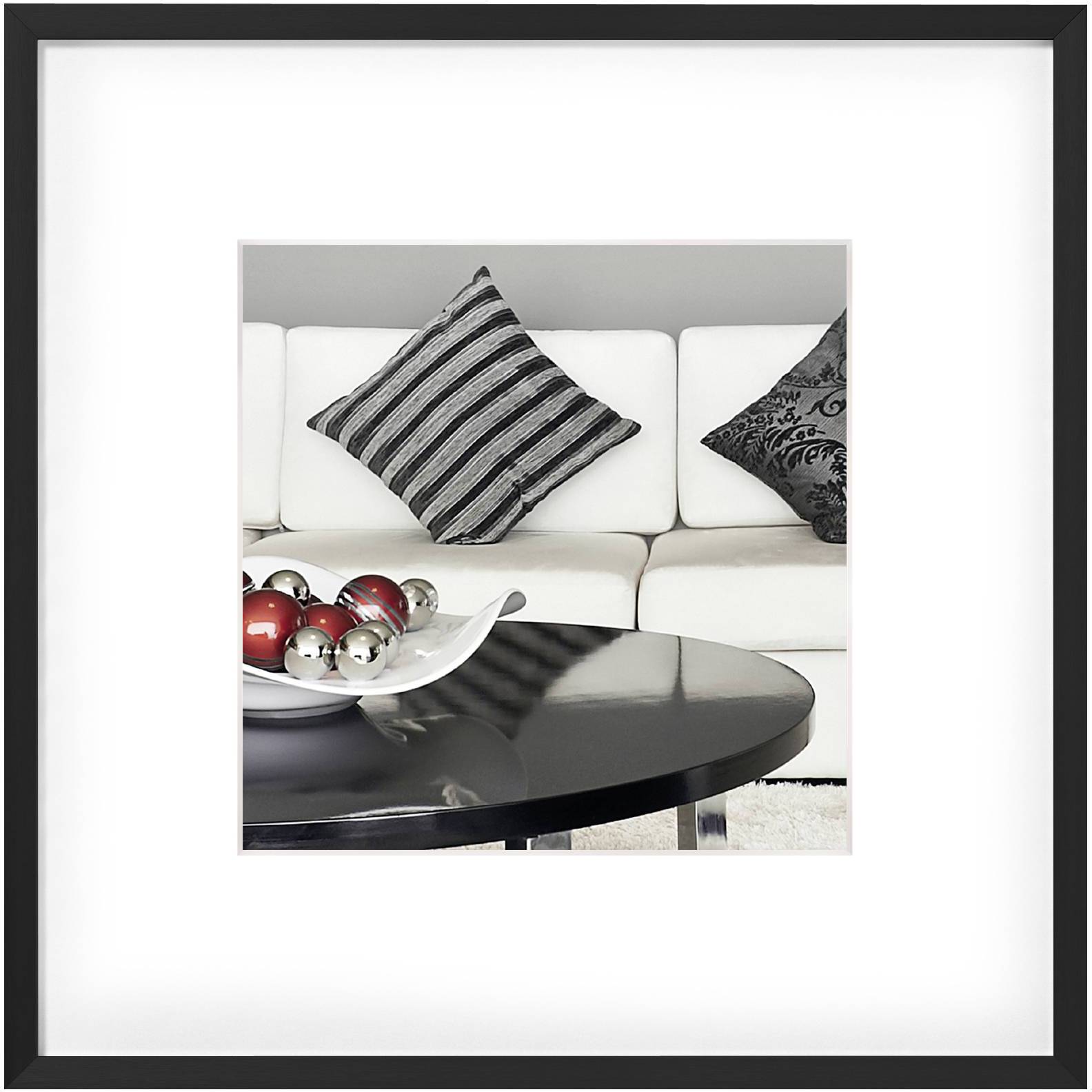 Moderne Wohnzimmerszene mit heller Couch, gestreiften Kissen und einem runden, dunklen Tisch mit dekorativen, glänzenden Kugeln.