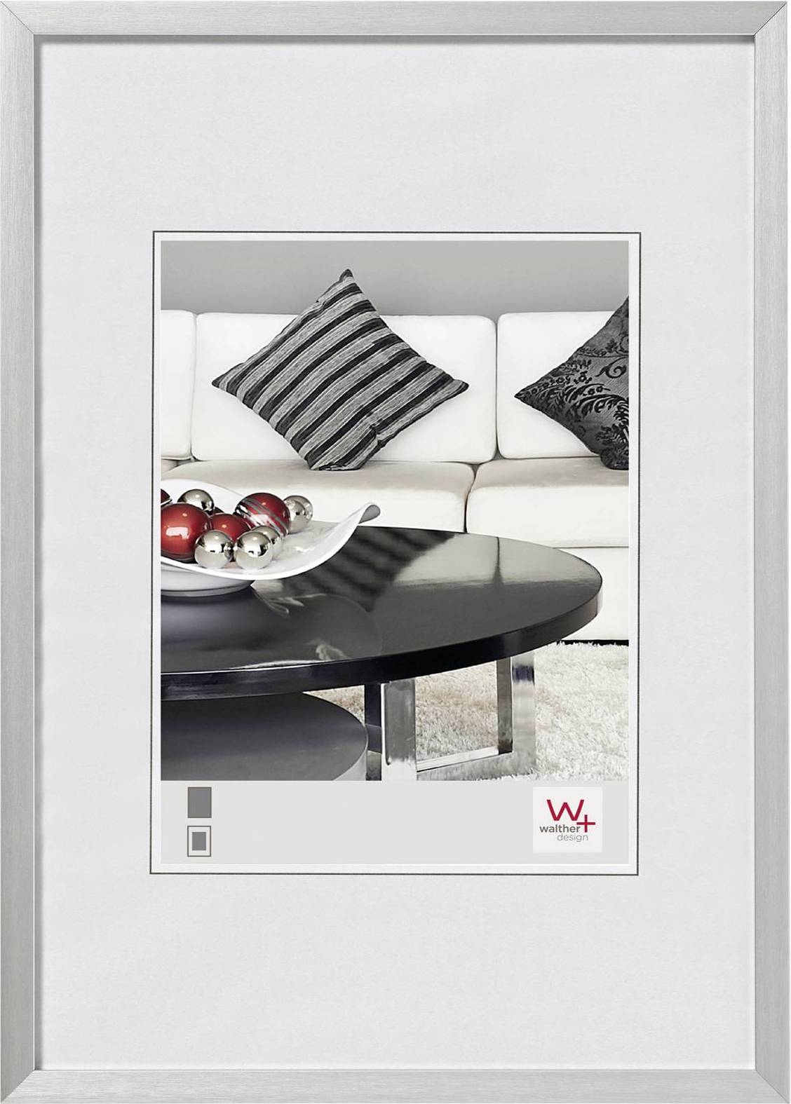 Ein Wohnzimmer mit weißem Sofa, dekorativen Kissen, einem schwarzen Couchtisch und einer Schale mit glänzenden roten und silbernen Kugeln.