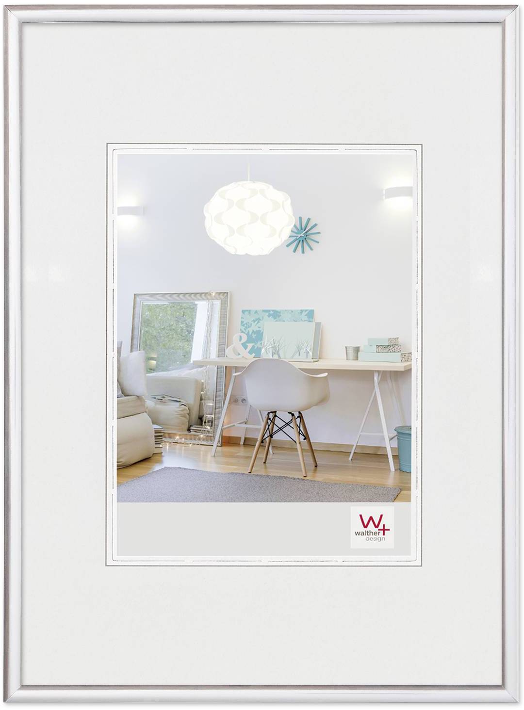 Ein moderner, heller Raum mit Schreibtisch, Eames-Stuhl, Spiegel und hellen Dekorationsgegenständen in einem weißen Bilderrahmen.