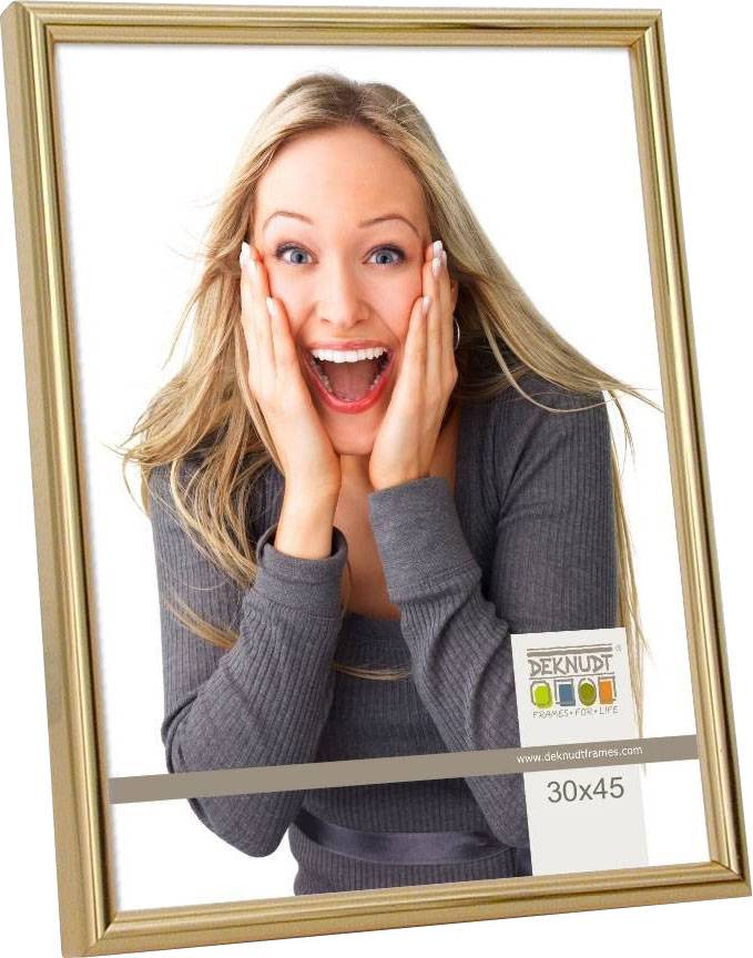 Eine lächelnde Person hält beide Hände an ihr Gesicht in einem goldenen Rahmen. Text auf dem Bild: 'DEKNUDT FRAMES FOR LIFE', Größe: 30x45.
