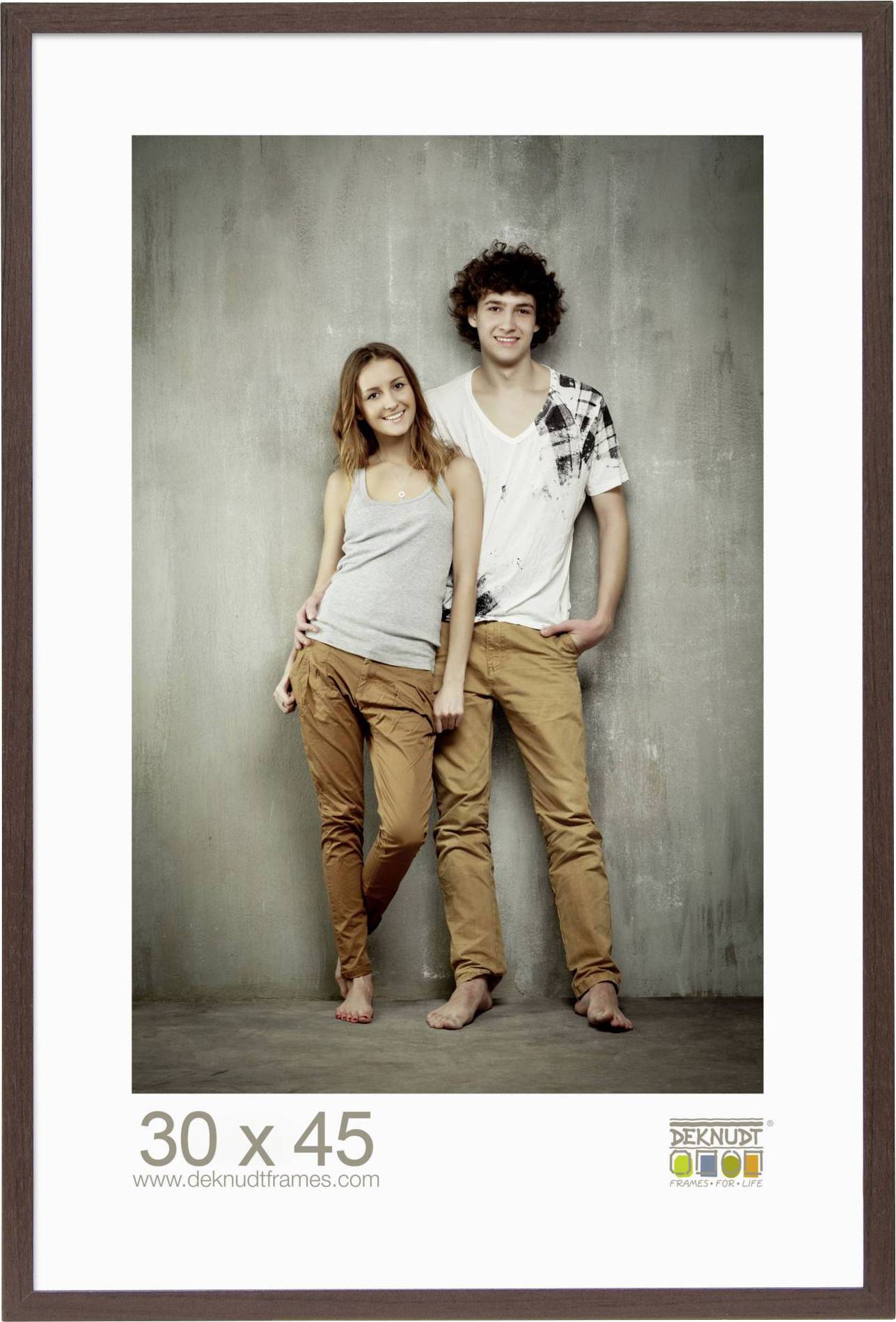 Ein Mann und eine Frau stehen eng nebeneinander, lächelnd in die Kamera, barfuß. Hinter ihnen eine neutrale Wand. Rahmeninformation unten.