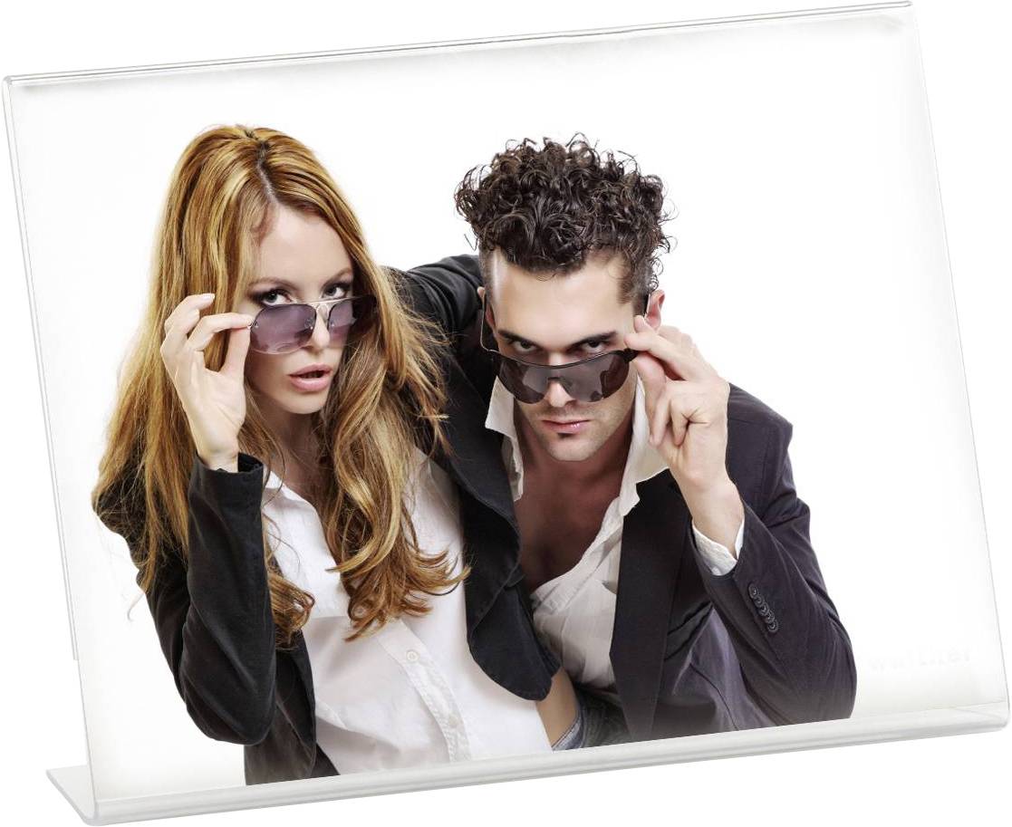 Zwei Personen in formeller Kleidung heben ihre Sonnenbrillen an, schauen in die Kamera, posieren selbstbewusst.