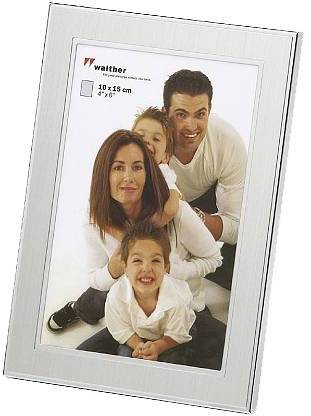 Eine lächelnde Familie, bestehend aus zwei Eltern und zwei Kindern, posiert fröhlich für ein Foto. Foto ist in einem silbernen Rahmen.