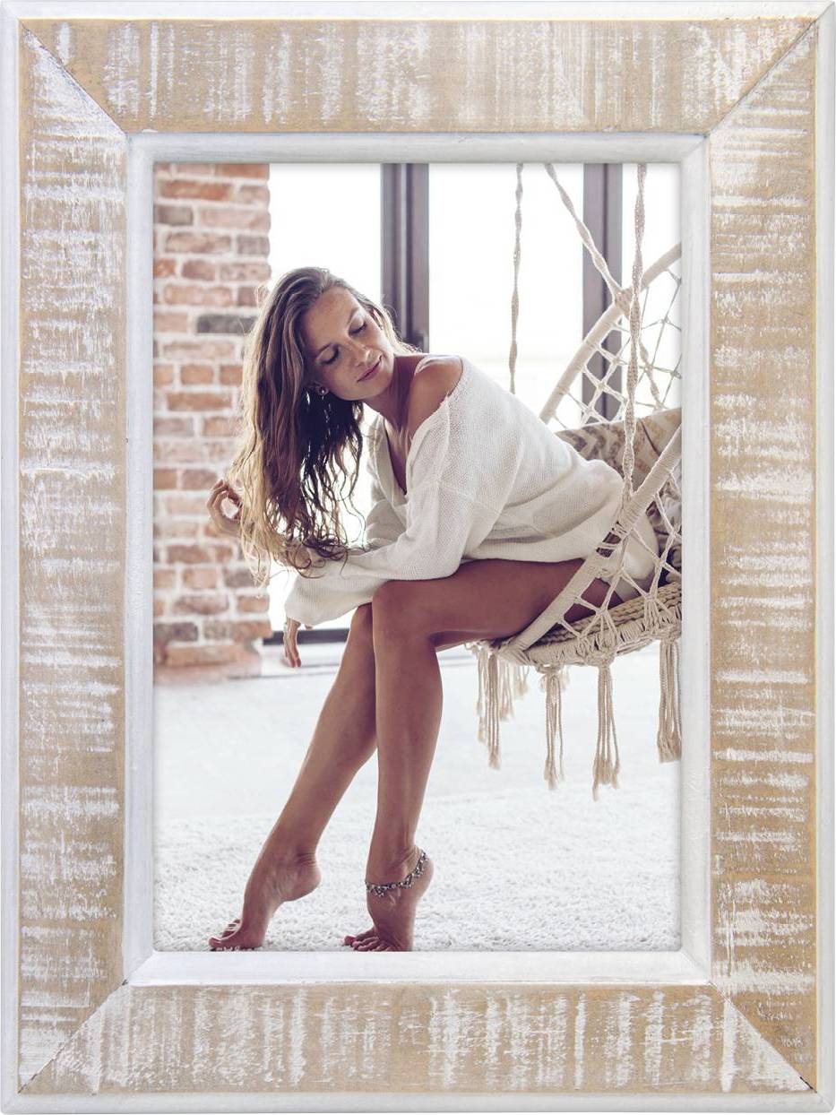 Frau sitzt entspannt in einem Hängehängesessel, trägt weiße Kleidung. Hintergrund aus Backstein und Glasfenstern.