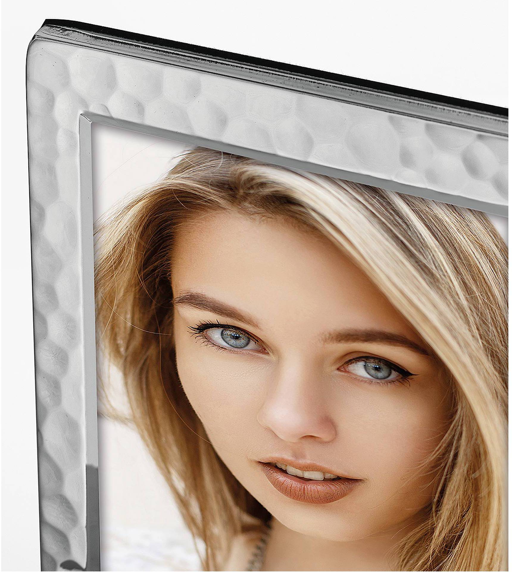 Ein gerahmtes Foto einer Frau mit langen blonden Haaren und blauen Augen. Der silberne Rahmen hat eine gehämmerte Textur.