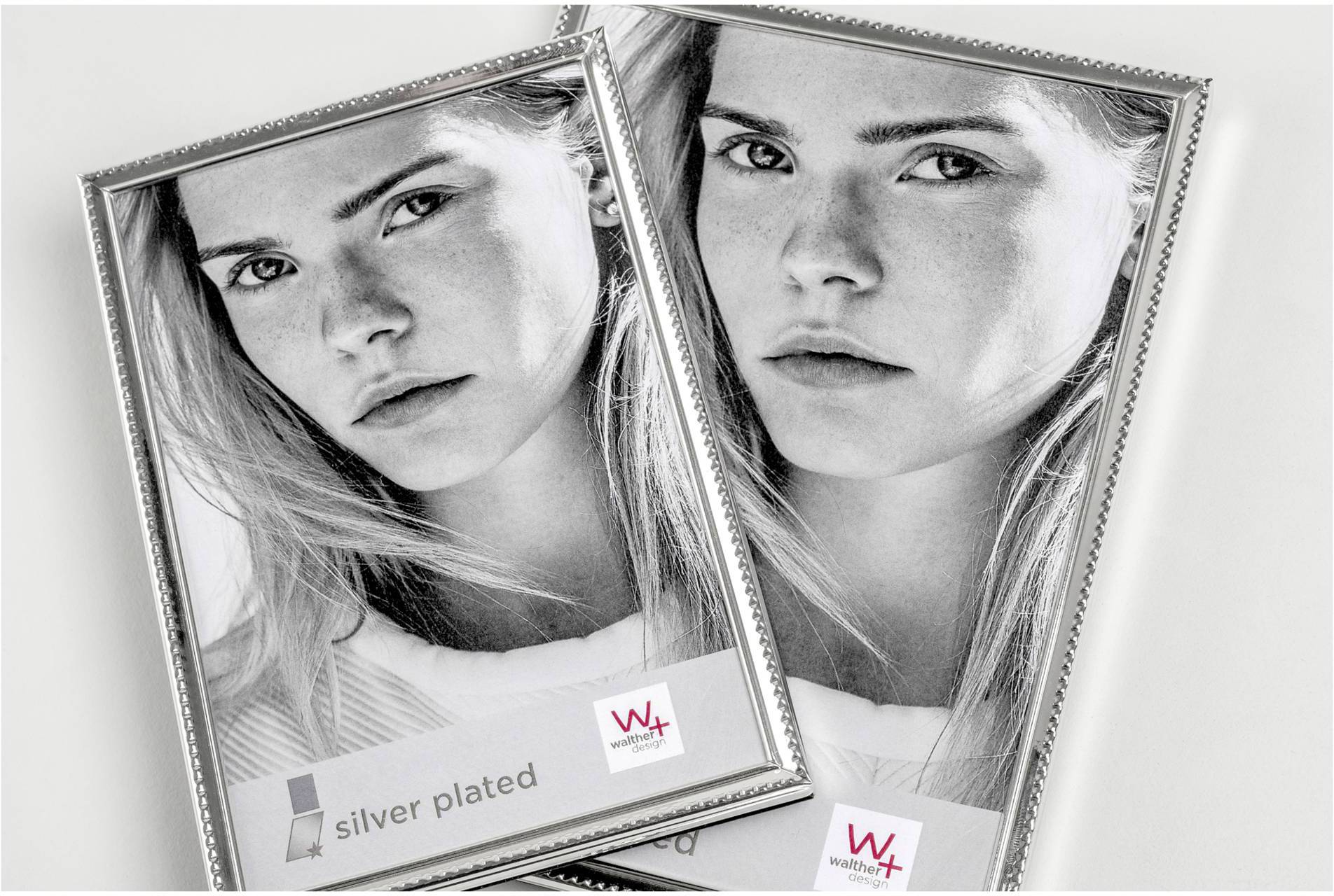Zwei silberne Bilderrahmen liegen überlappend. In jedem Rahmen befindet sich das gleiche Schwarz-Weiß-Porträt einer Frau.
