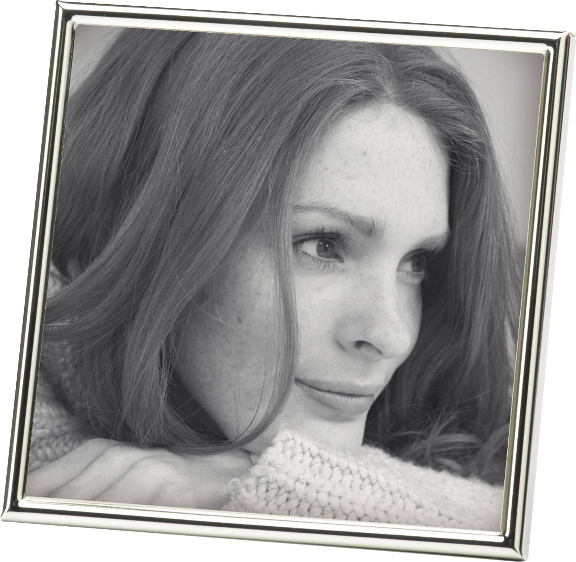 Eine Frau mit langen Haaren lächelt und blickt zur Seite. Sie trägt einen Strickpullover. Das Bild ist in einem silbernen Rahmen.