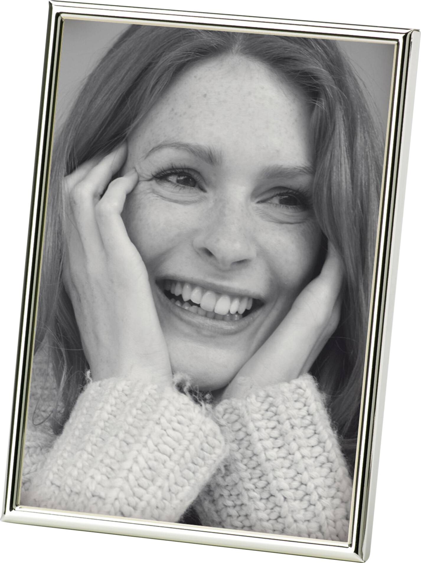 Eine Frau lächelt und hält ihr Gesicht mit den Händen. Sie trägt einen gestrickten Pullover und schaut nach links.