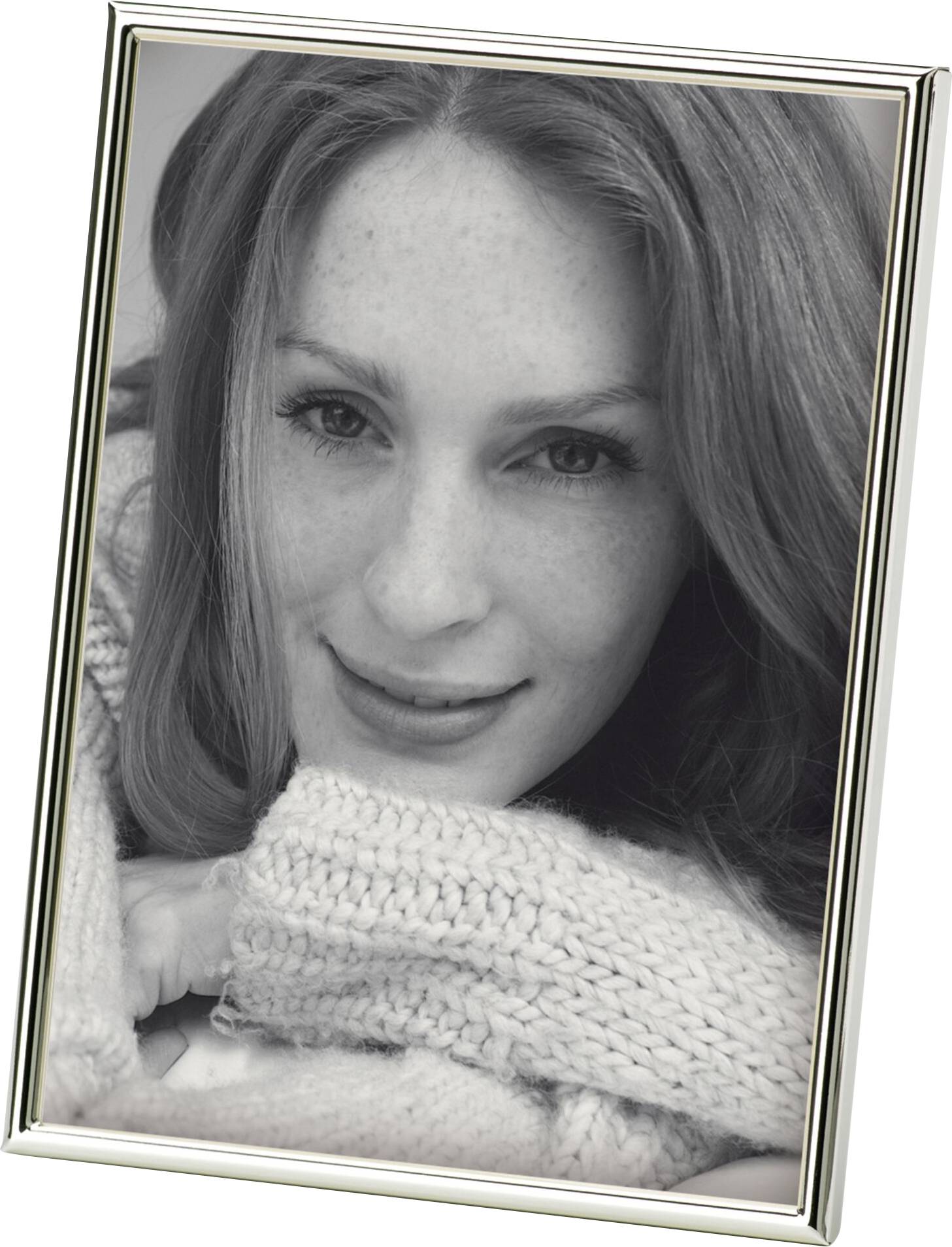Eine lächelnde Frau mit langen, glatten Haaren trägt einen grob gestrickten Pullover. Schwarzweiß-Fotografie in einem Rahmen.