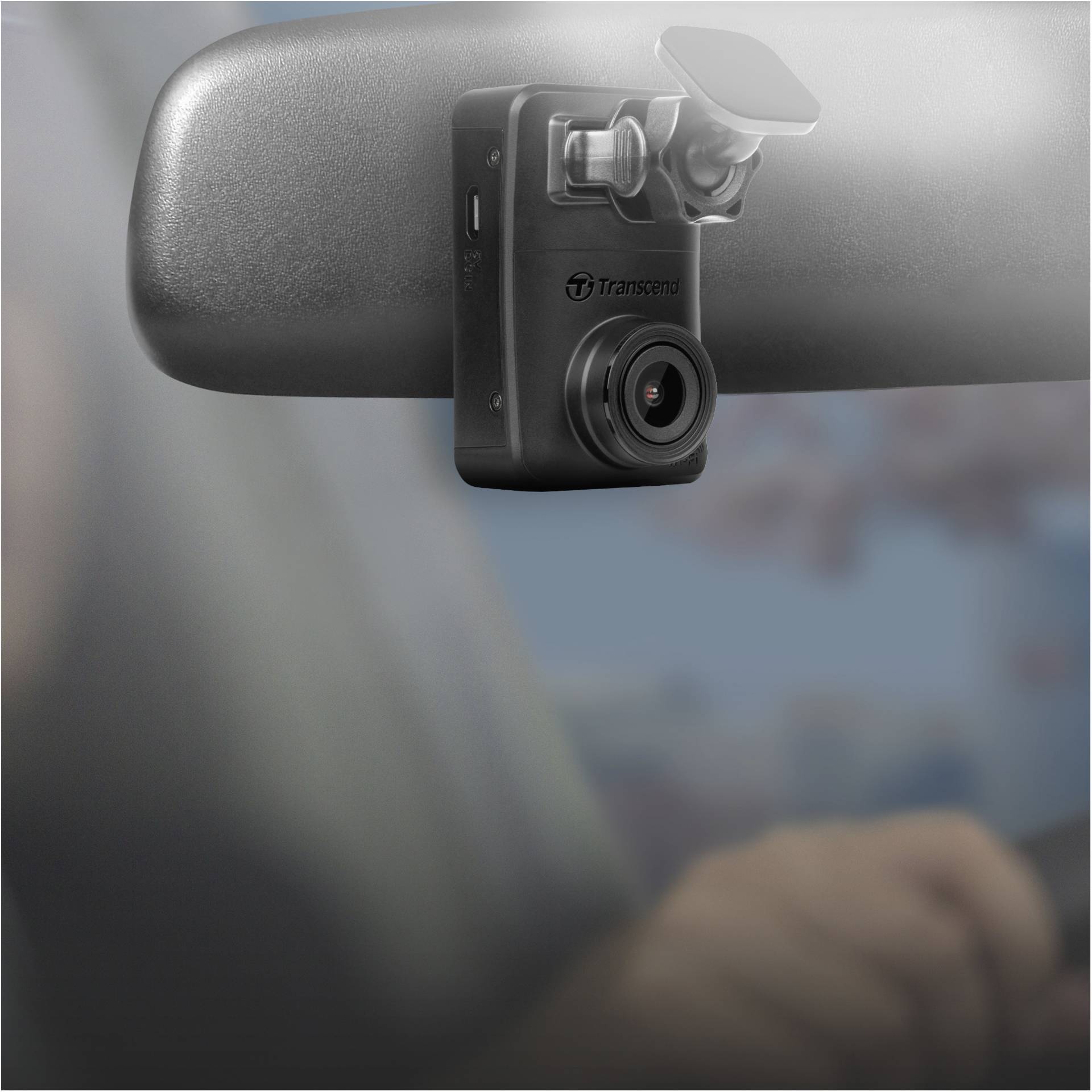 Eine schwarze Dashcam ist am Rückspiegel eines Autos befestigt. Sie zeigt in den Innenraum und dokumentiert die Fahrt.