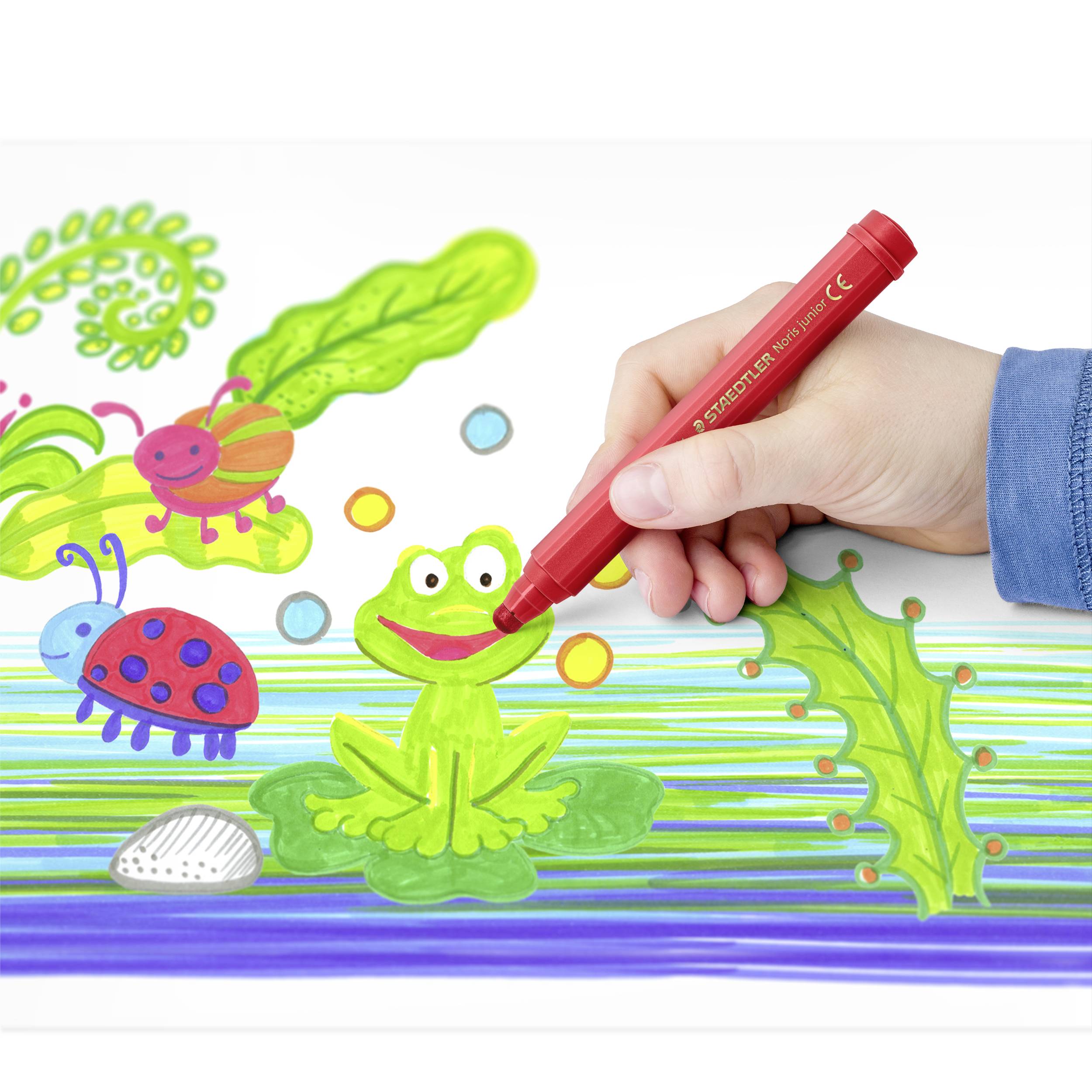 Eine Hand zeichnet mit einem roten Filzstift auf einem farbenfrohen Bild, das einen grünen Frosch, eine Marienkäfer und eine Raupe zeigt.