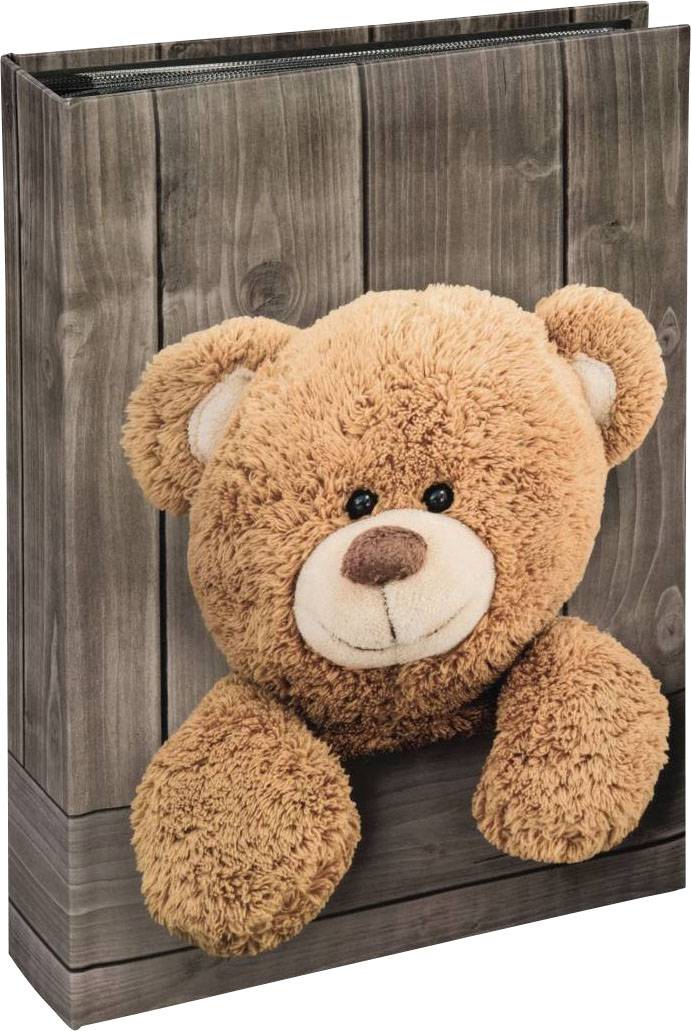 Ein Plüschteddybär sitzt in einem hölzernen Regal, der Kopf und die Vorderpfoten ragen heraus. Der Hintergrund ist aus Holzlatten.