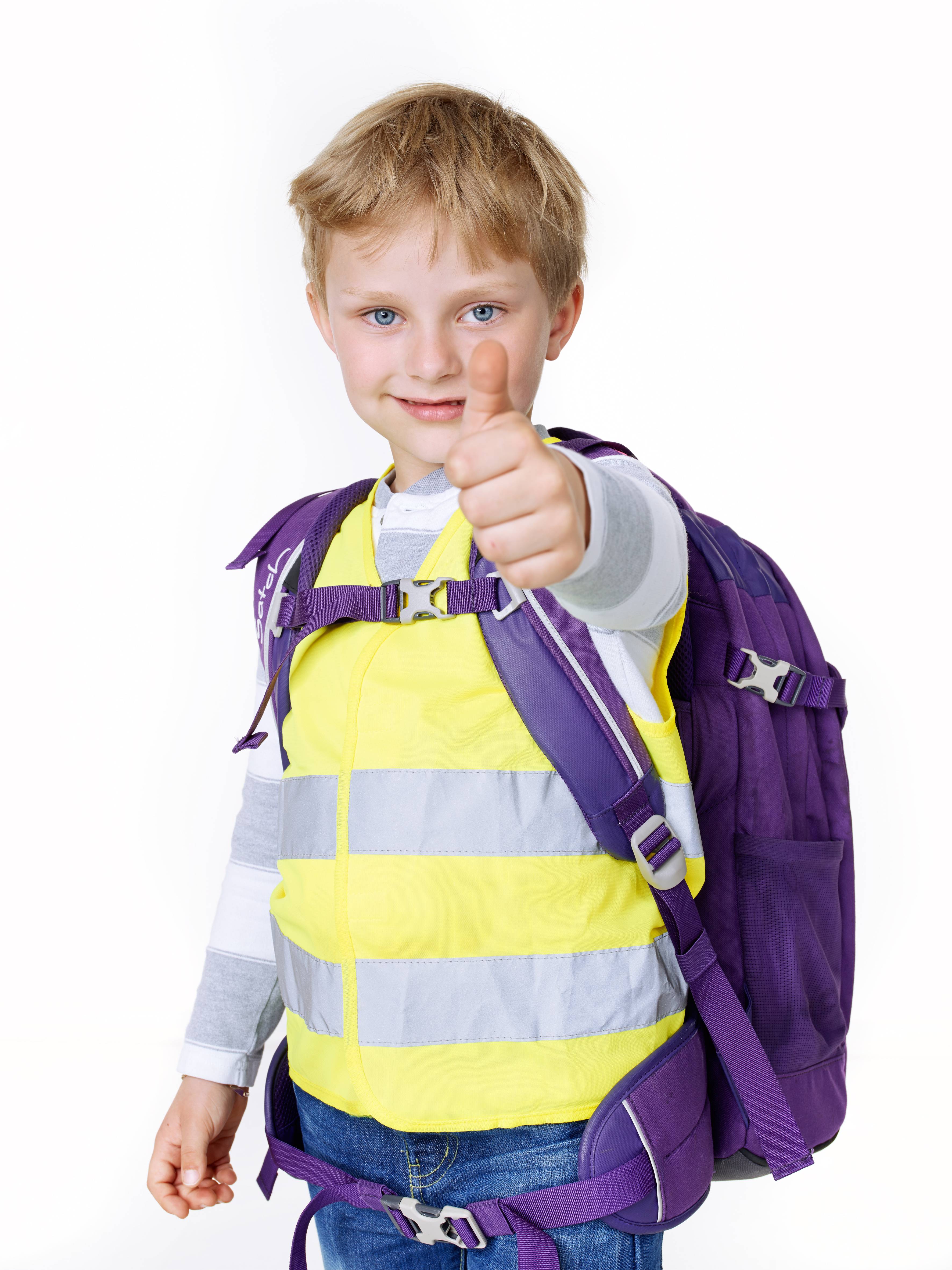 Ein Junge mit gelber Warnweste und violettem Rucksack zeigt den Daumen hoch.
