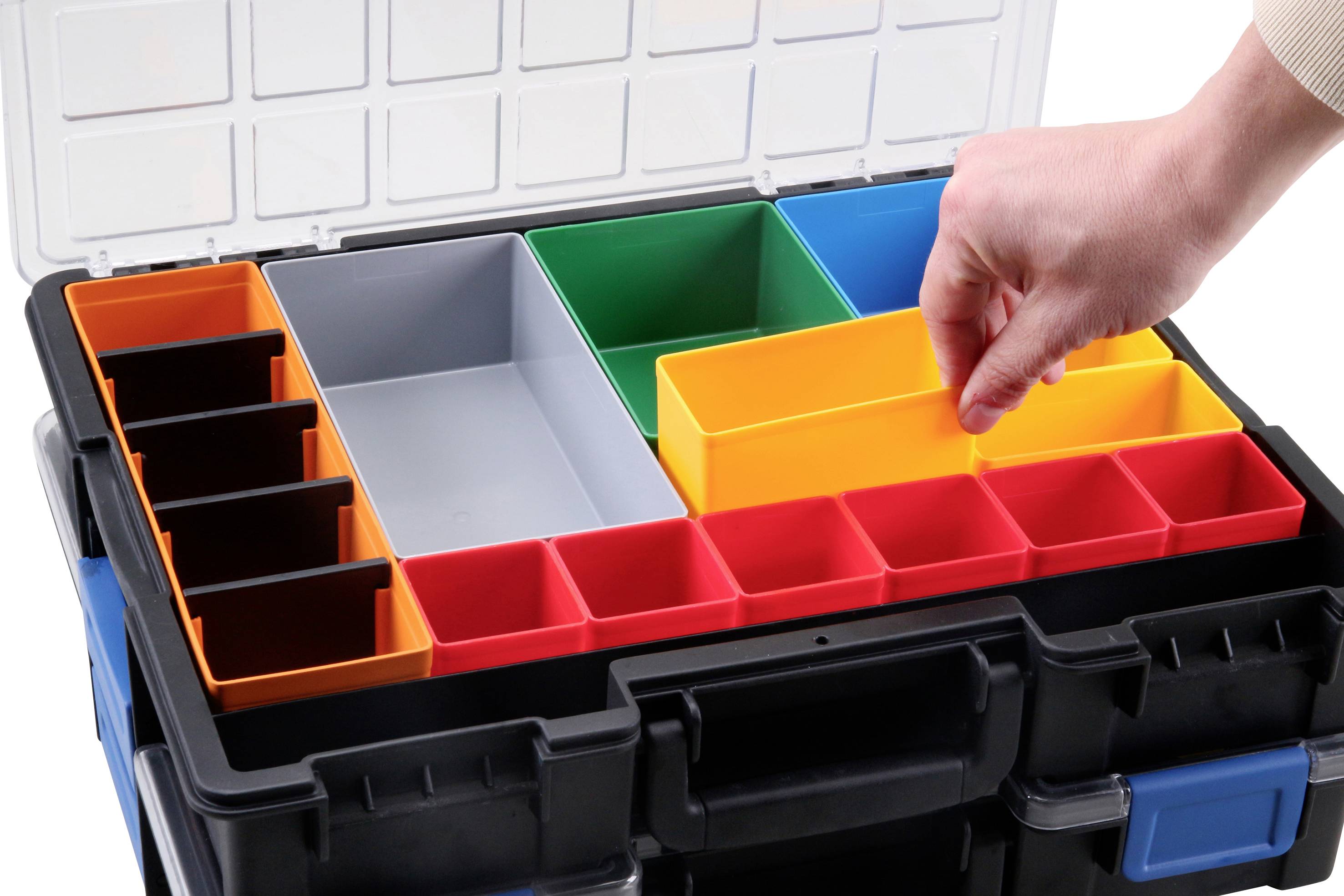 Eine Hand ordnet bunte, herausnehmbare Behälter in einer offenen Sortierbox. Die Box hat Platz für unterschiedliche Behältergrößen.