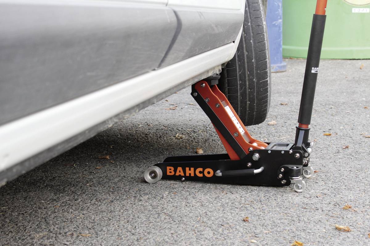 Nahaufnahme eines Autos, das mit einem hydraulischen Wagenheber angehoben wird.